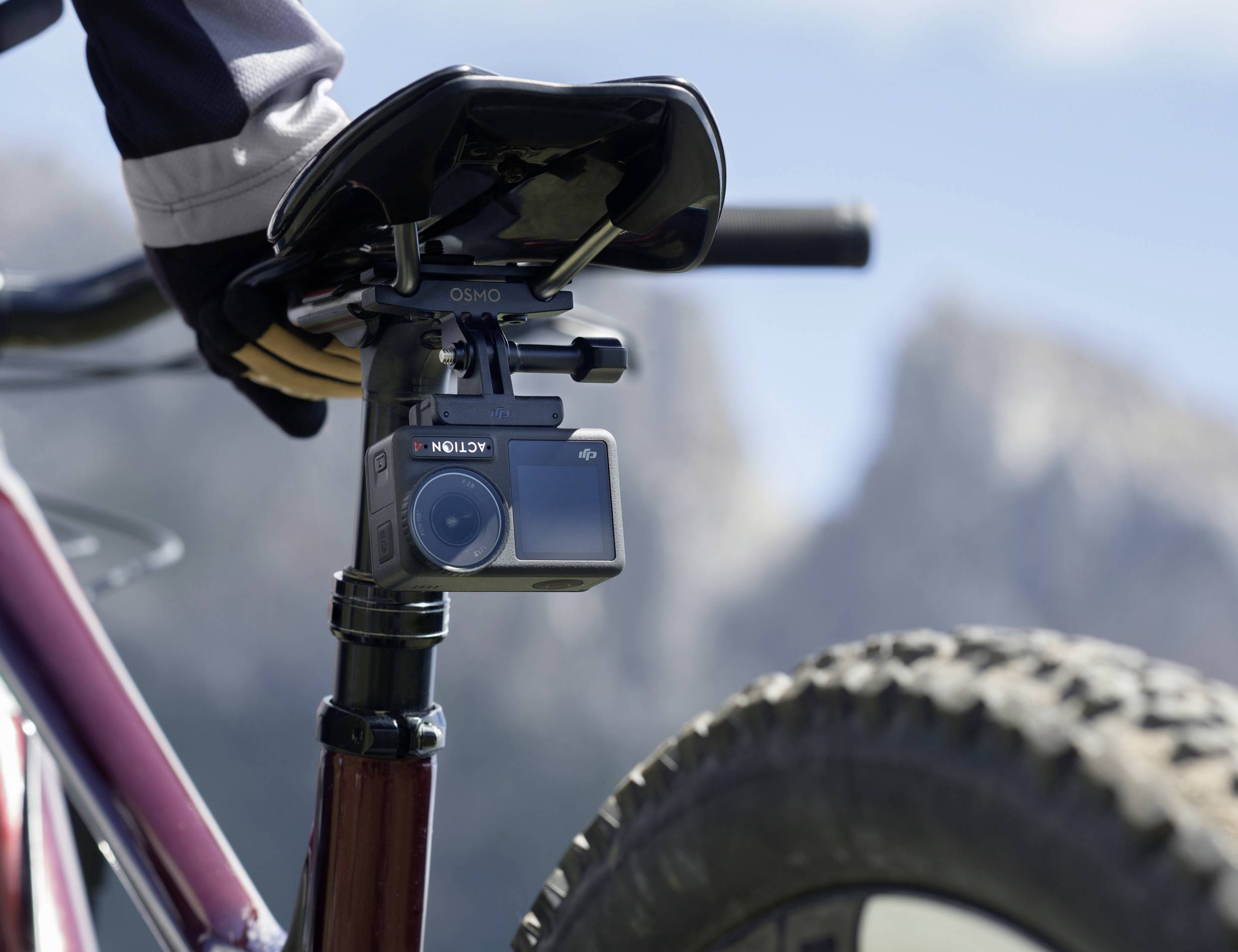 Una action camera è montata sotto la sella della bicicletta. Sullo sfondo si vedono montagne sfocate.