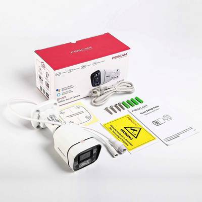 Una telecamera di sorveglianza con confezione e accessori, tra cui cavi, viti e istruzioni, posizionata su un tavolo.