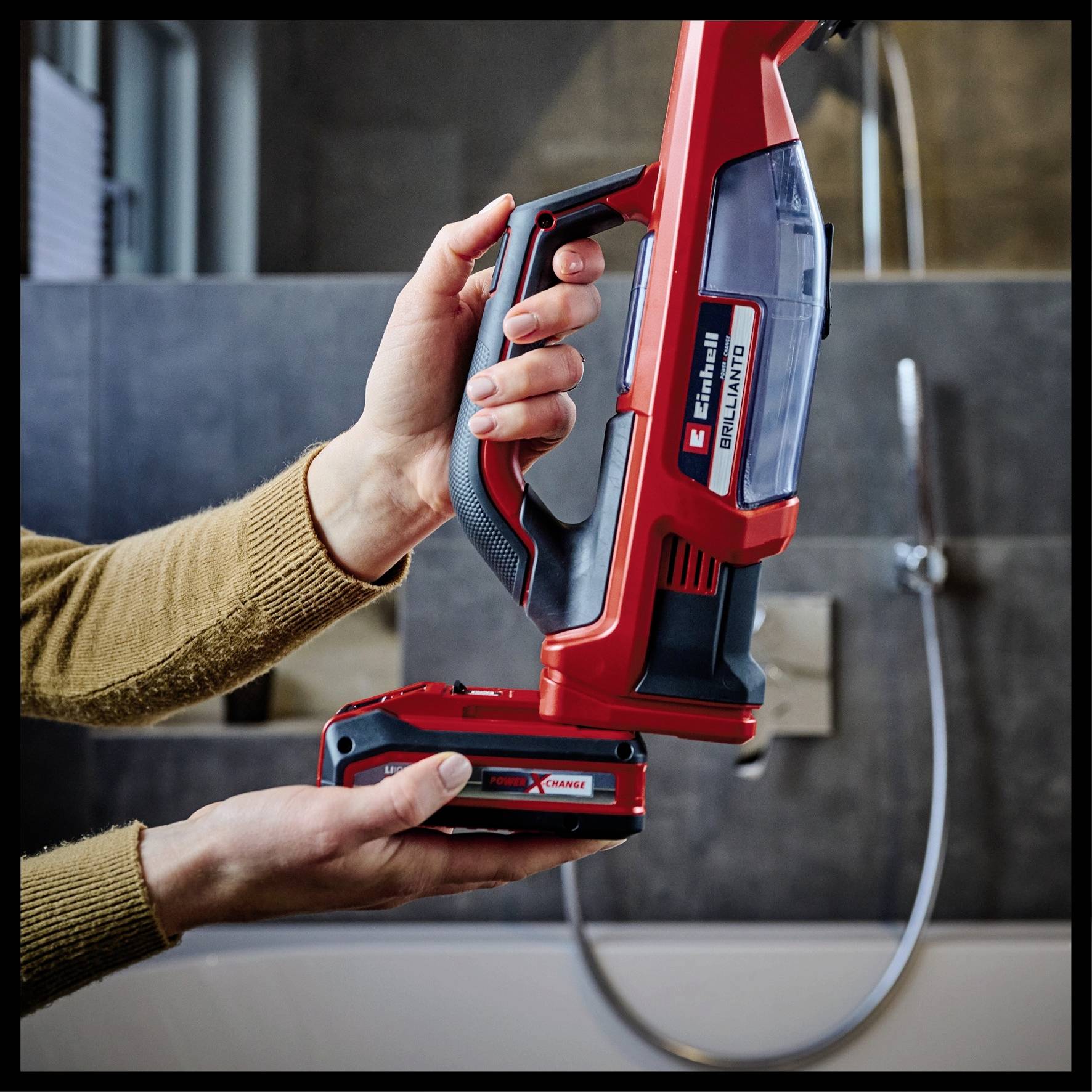 Una persona tiene un aspirapolvere senza fili sopra un rubinetto del bagno, pronta a utilizzarlo.