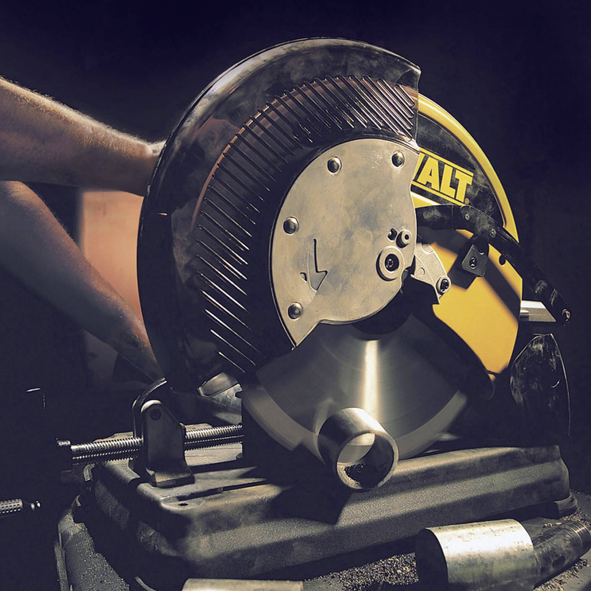 Una persona sta lavorando con una sega circolare elettrica che taglia il metallo. Scintille volano, e l'ambiente è buio.