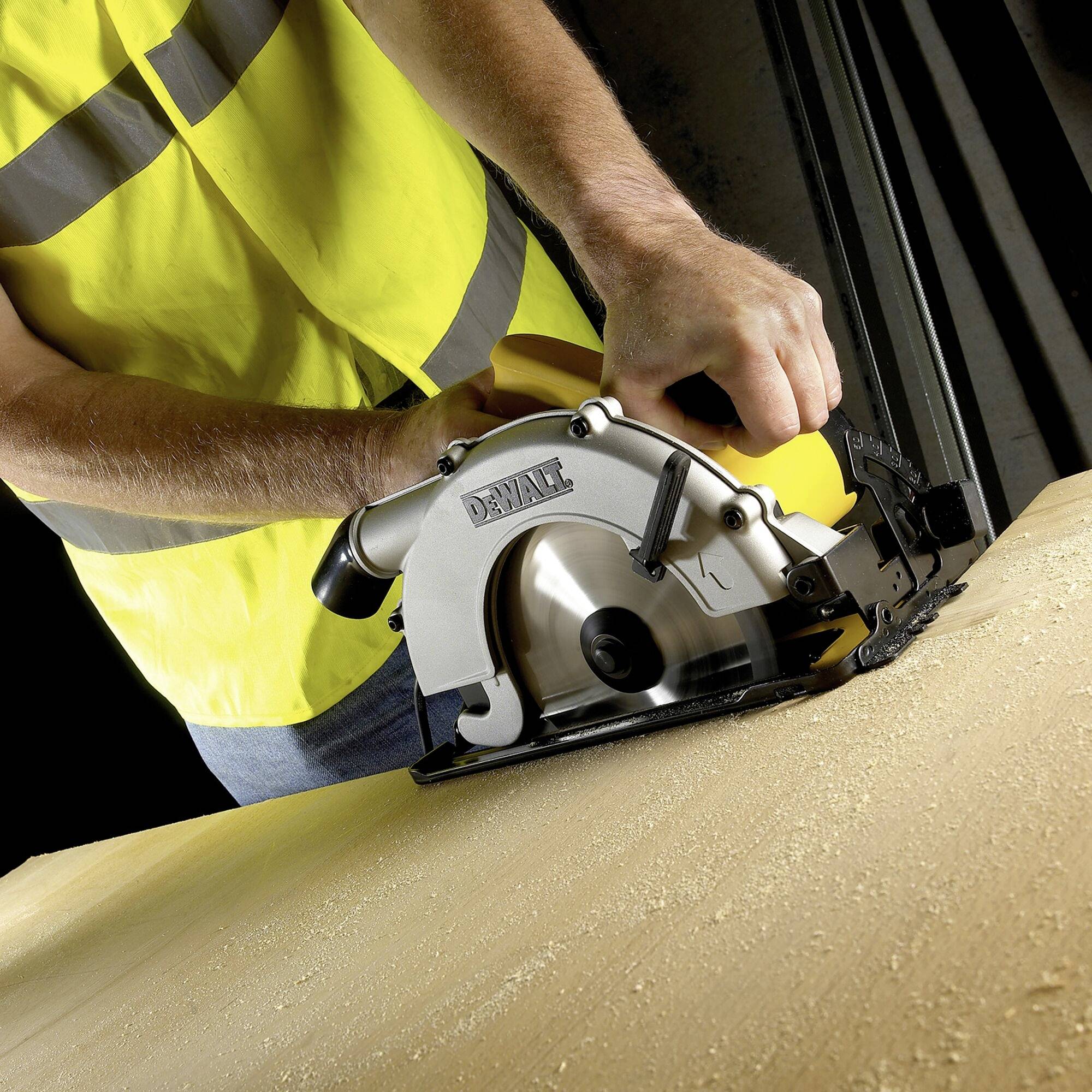 Una persona con un gilet giallo taglia un pezzo di legno con una sega circolare elettrica. Focus sulla precisione del lavoro.