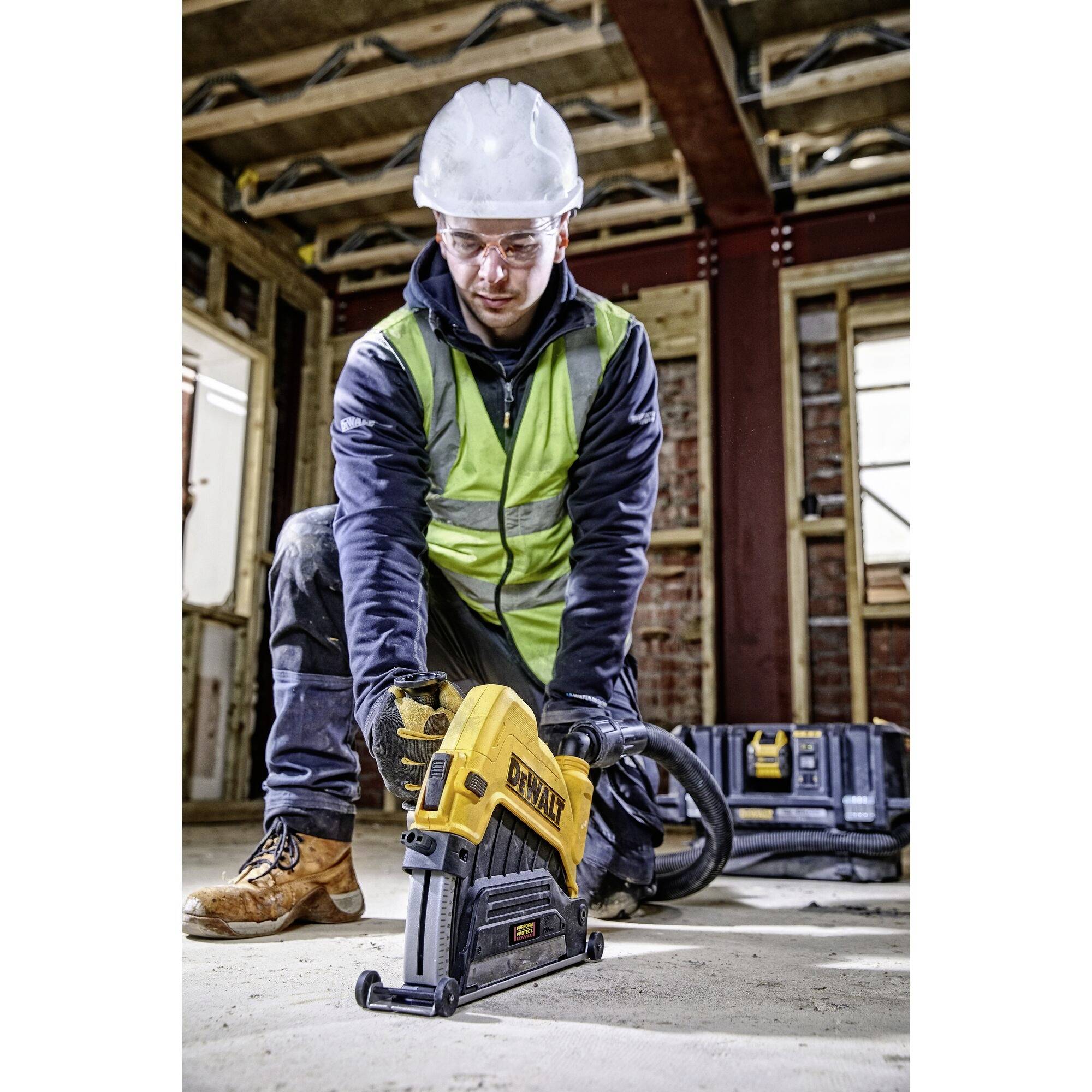 Una persona in abbigliamento protettivo e casco sta utilizzando un attrezzo in un cantiere edile in fase di costruzione. L'attenzione è concentrata sulla situazione lavorativa.