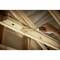Un cacciavite avvita una vite di legno in una trave di legno nel sottotetto. Una mano tiene saldamente il cacciavite.