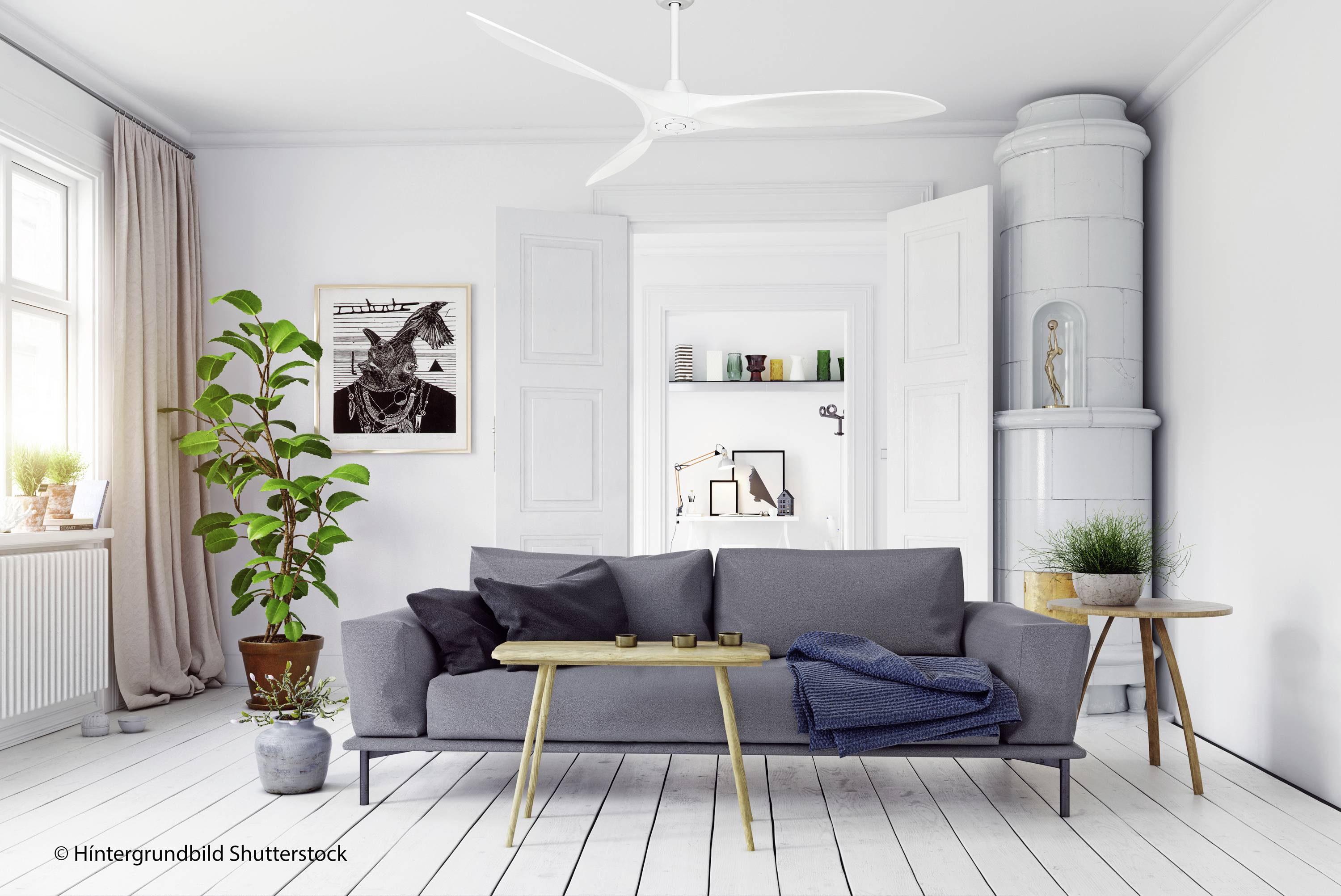 Soggiorno luminoso con divano grigio, tavolino da caffè moderno, piante e opera d'arte. Pareti bianche, stufa a legna e ventilatore a soffitto.