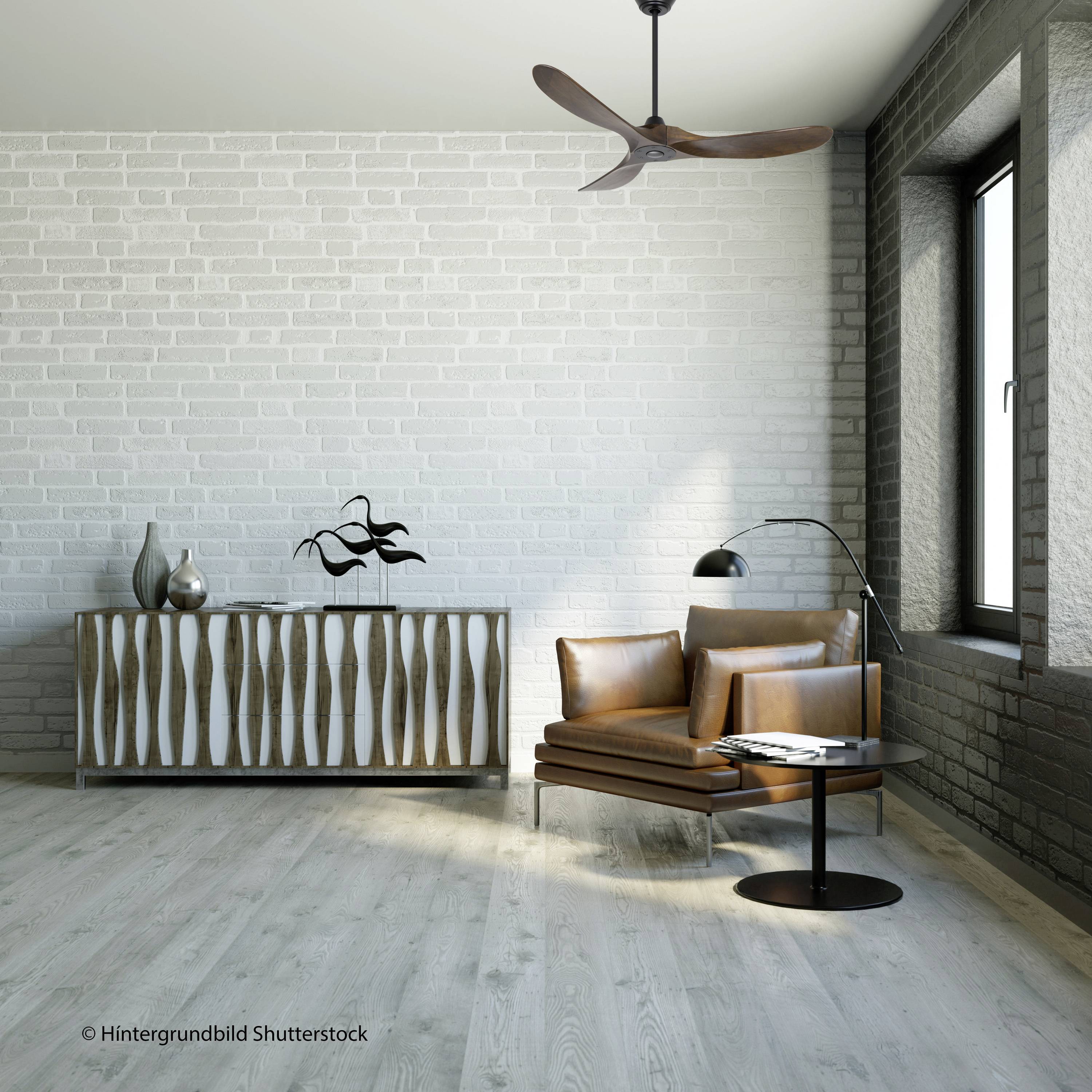Un soggiorno arredato in stile moderno con parete in mattoni grigio chiaro, poltrona in pelle marrone, lampada da terra e credenza con frontali in metallo.