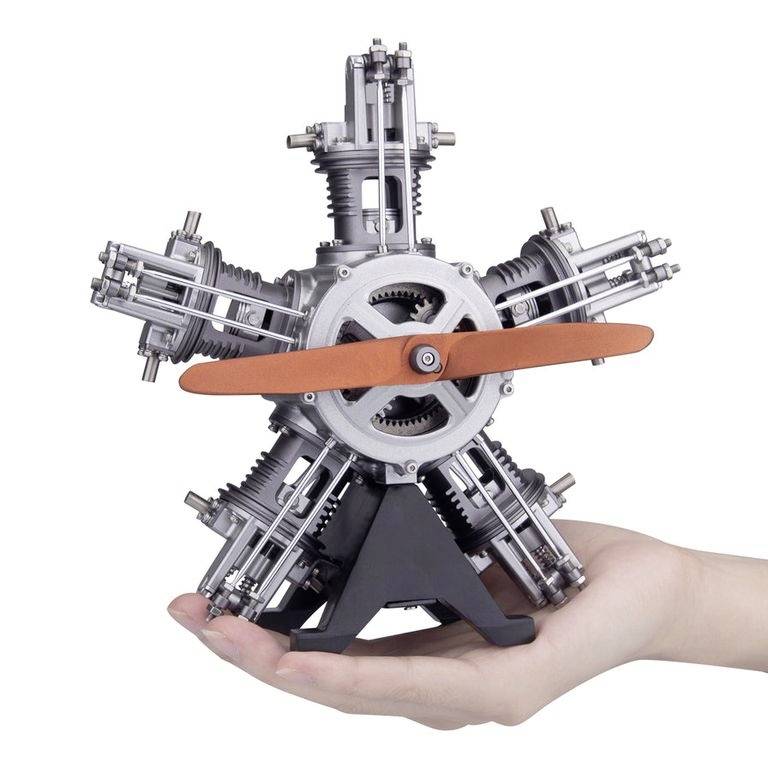 Un piccolo modello di motore stellare viene tenuto in mano. Il motore ha cinque cilindri e pale dell'elica arancioni.