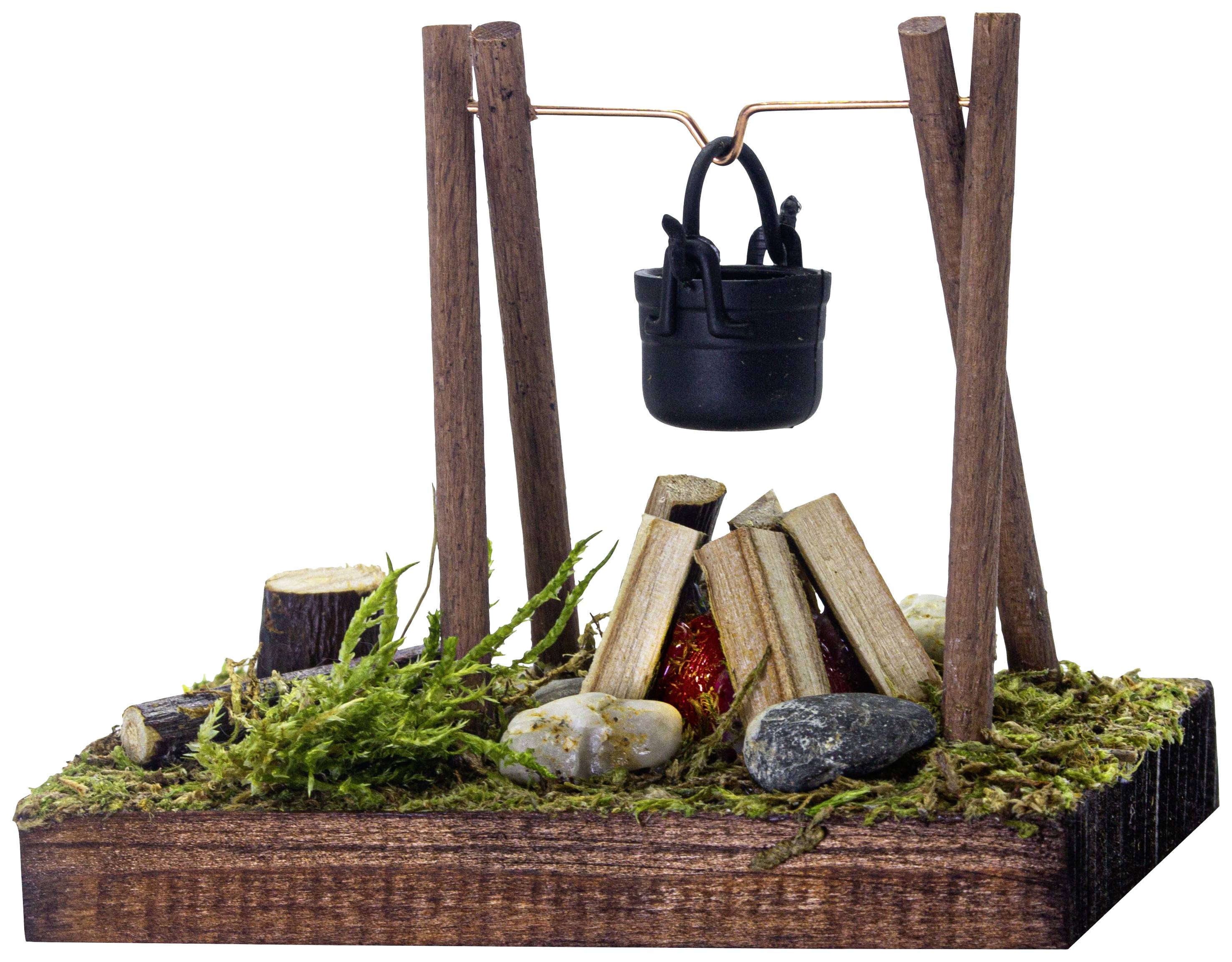 Miniatura di campeggio con struttura in legno, pentola sospesa e fuoco da campo, circondato da muschio e pietre su base lignea.