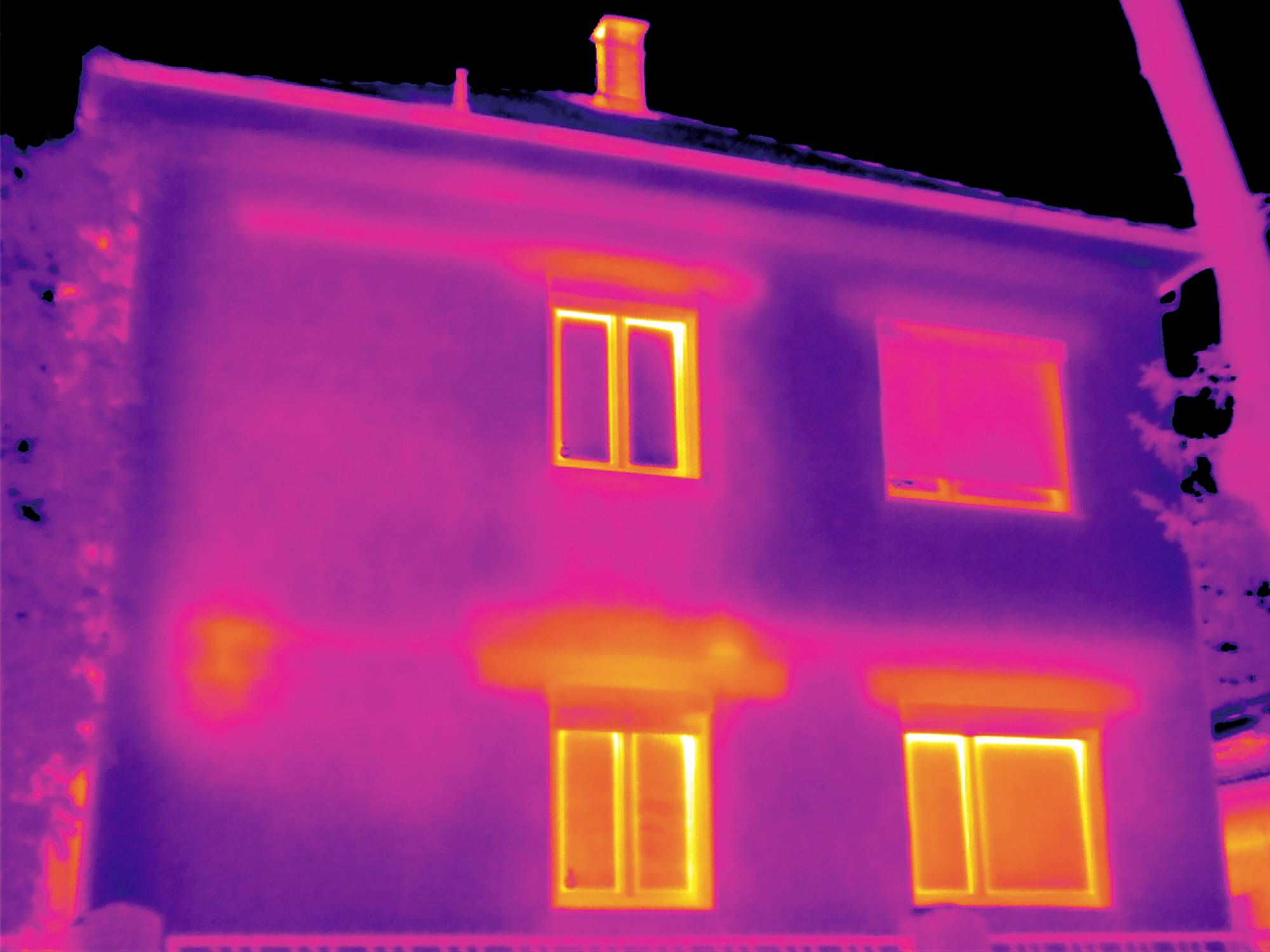 Un'immagine termografica di una casa a due piani. Le aree chiare indicano perdite di calore in corrispondenza di finestre e pareti.