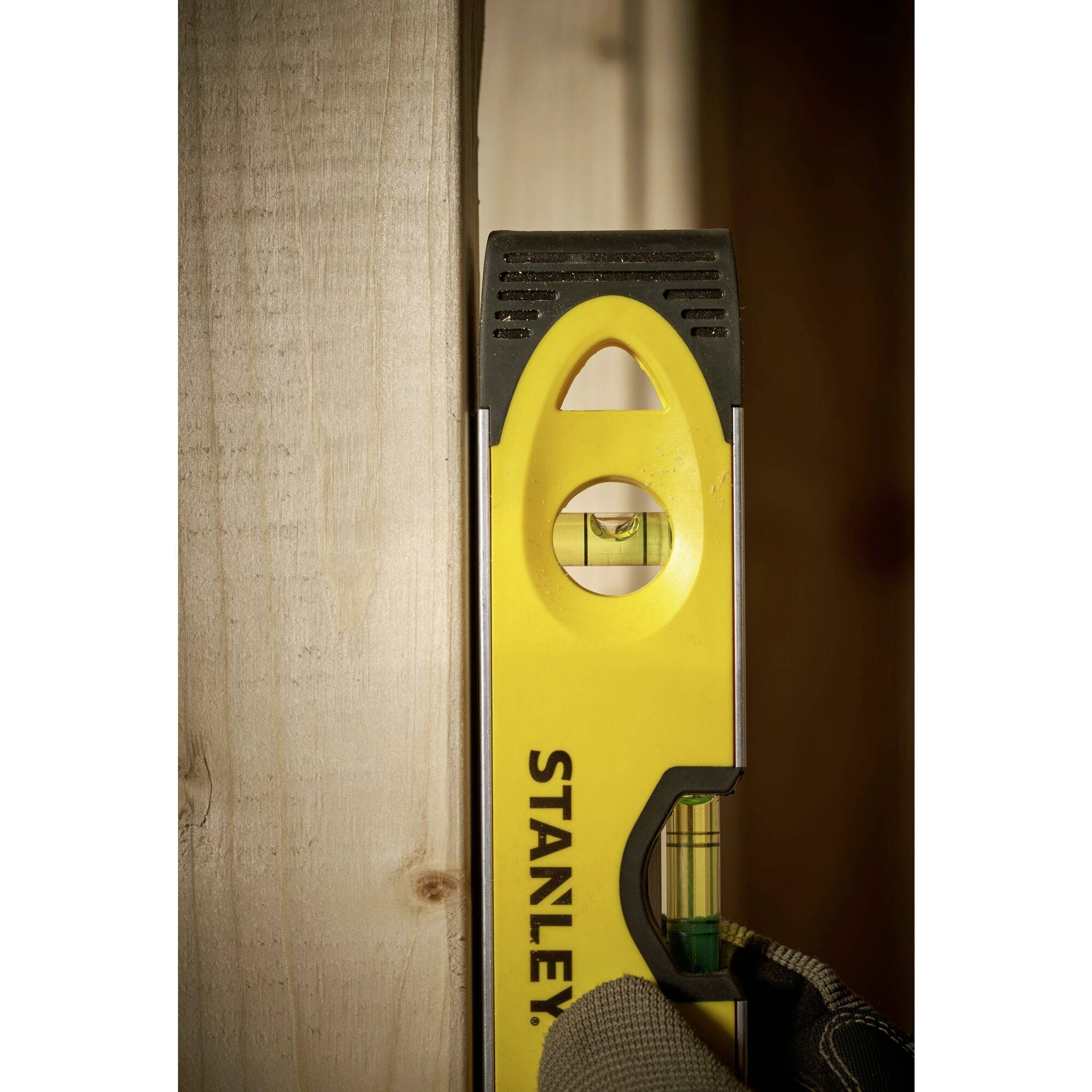Livella su un'asse di legno indica il livellamento. La bolla nel vetrino è centrata e mostra che l'asse è dritto. Sfondo sfocato.