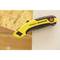 Un cutter giallo Stanley FatMax è posizionato su una tavola di legno.