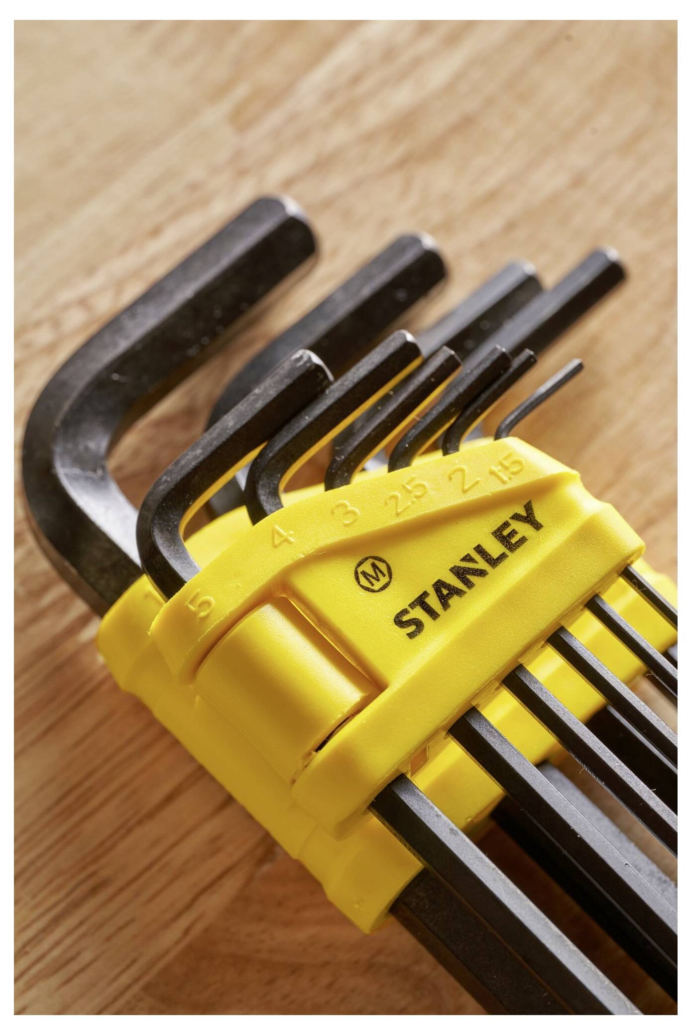 'Set di chiavi a brugola in un supporto giallo su un tavolo di legno, con taglie da 1,5 a 10 mm indicate. Nome del marchio visibile.'
