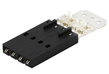 Un connettore elettrico nero rettangolare con quattro punti di connessione e un clip di fissaggio bianco e piatto in alto.