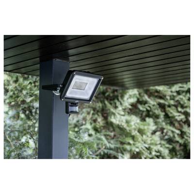 Faro di sicurezza per esterni nero montato su un palo del patio sotto un tetto, rivolto verso il giardino.