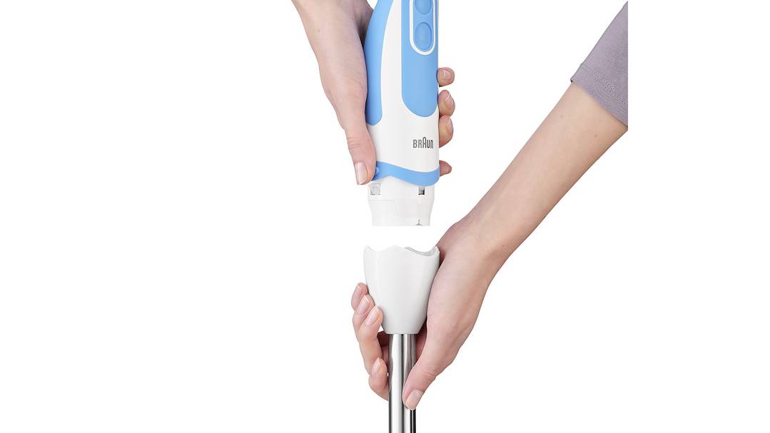 Una persona tiene e collega un accessorio blu per frullatore a immersione. Le mani avvolgono le parti di giunzione del frullatore e dell'asta.