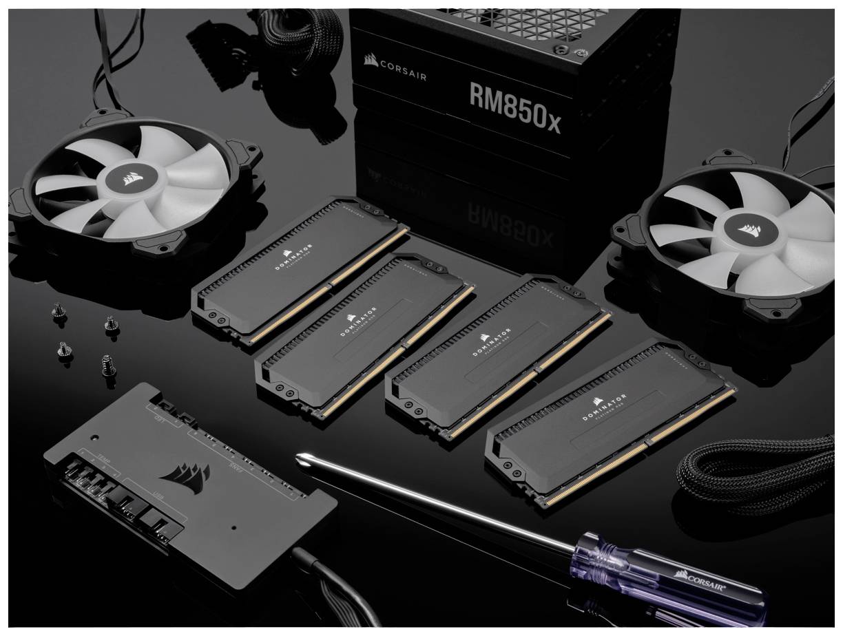 Un kit per computer con ventole, moduli RAM e componenti dell'alimentatore su una superficie nera. Include attrezzi e cavi.