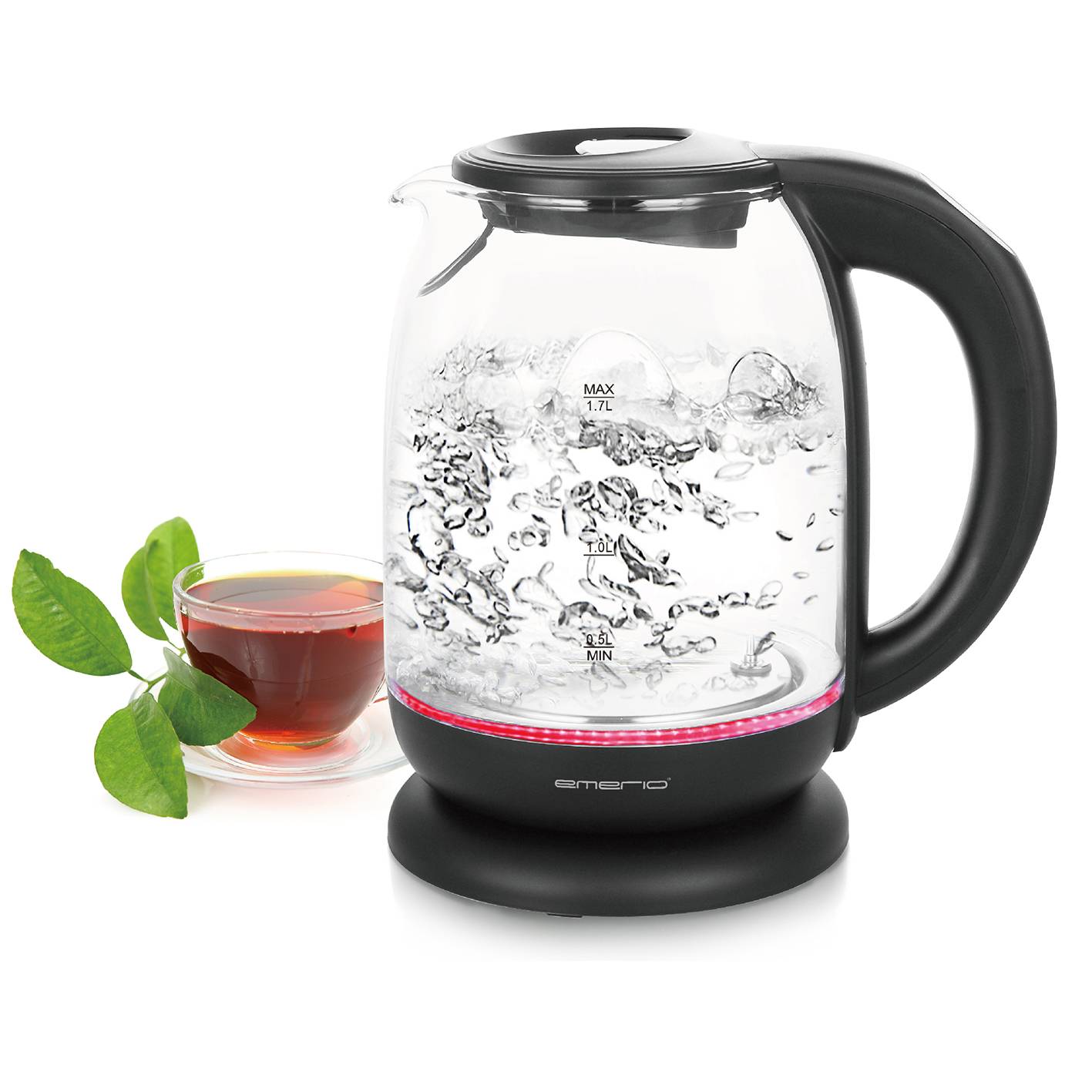 Una bollitrice di vetro con acqua bollente, accanto un bicchiere di tè e foglie verdi. La bollitrice ha indicatori per i livelli dell'acqua.