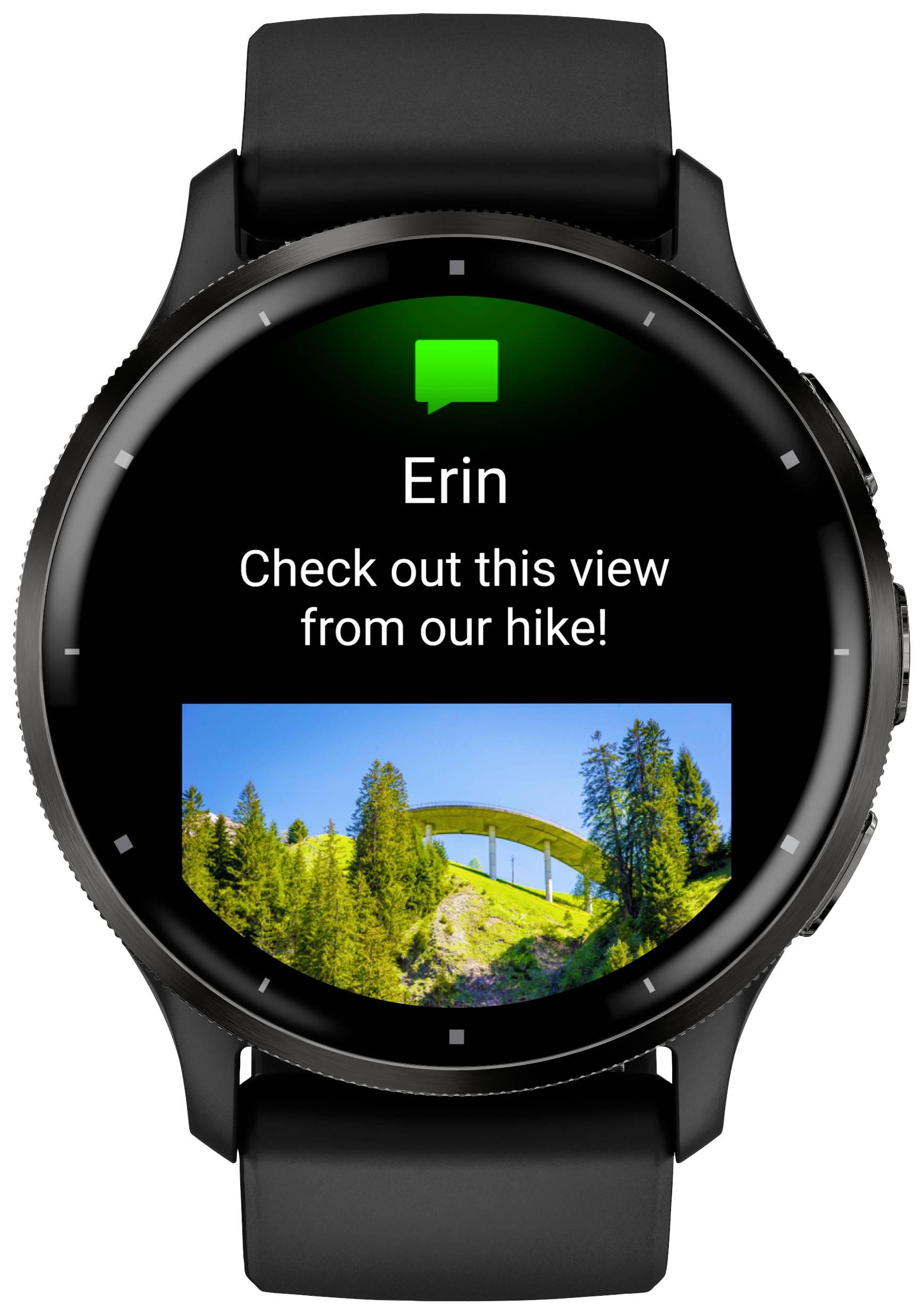 Un smartwatch nero mostra un messaggio di 'Erin': 'Dai un'occhiata a questa vista dal nostro trekking!' con una foto di un ponte in un paesaggio boschivo.