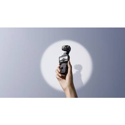 Una mano tiene una fotocamera compatta con schermo, mostrando un'immagine di montagna. La fotocamera è posizionata su uno sfondo grigio.