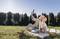 Una donna e un bambino seduti su una coperta all'aperto mentre si fanno un selfie. Un cestino da picnic con delle mele è accanto a loro. Sullo sfondo ci sono degli alberi.