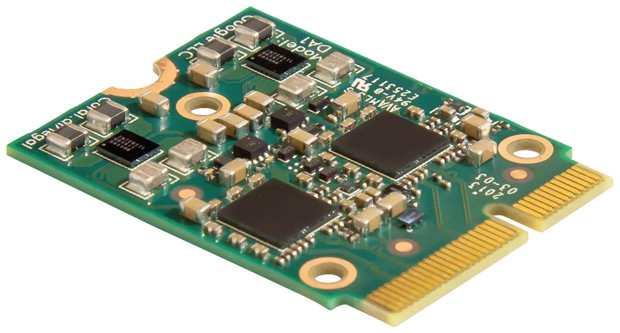 Una scheda verde con diversi circuiti integrati e bordi di connessione dorati. Contiene condensatori e resistori.