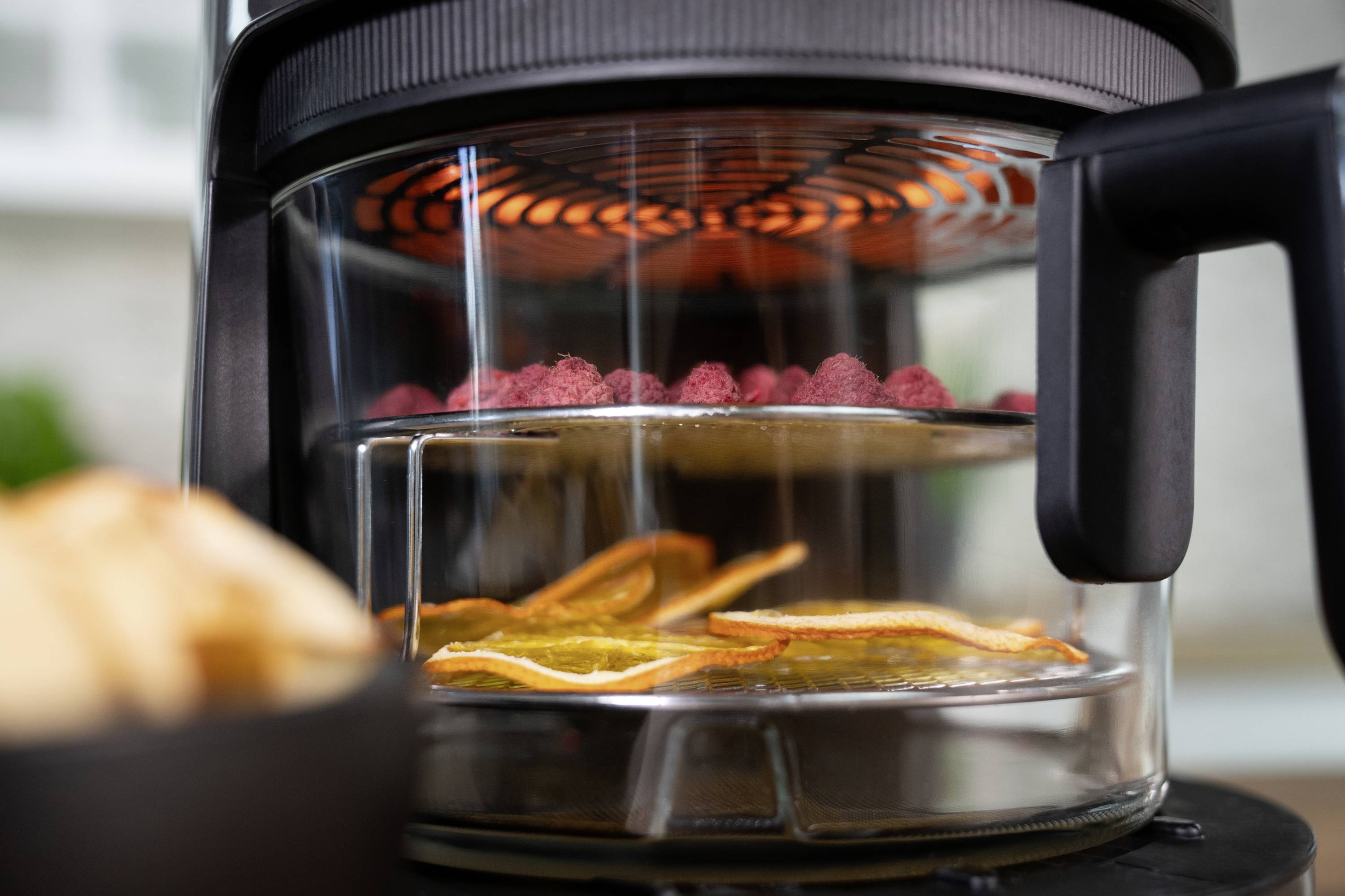 Un essiccatore di frutta essicca fette di frutta rossa e arancione. Un ventilatore garantisce una distribuzione uniforme del calore.