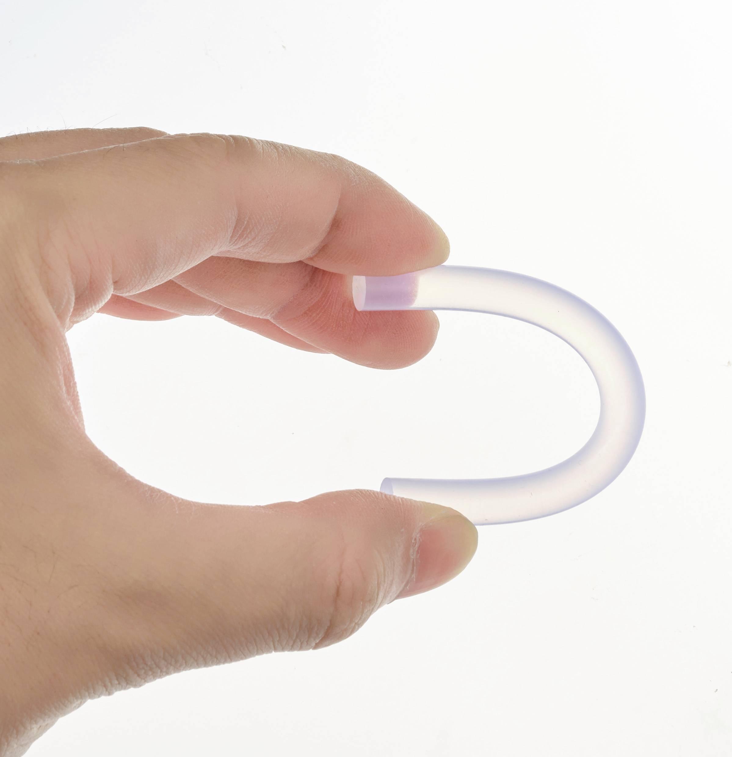 Una mano tiene un oggetto trasparente e curvo che assomiglia a un piccolo U. La luce filtra leggermente attraverso il materiale.