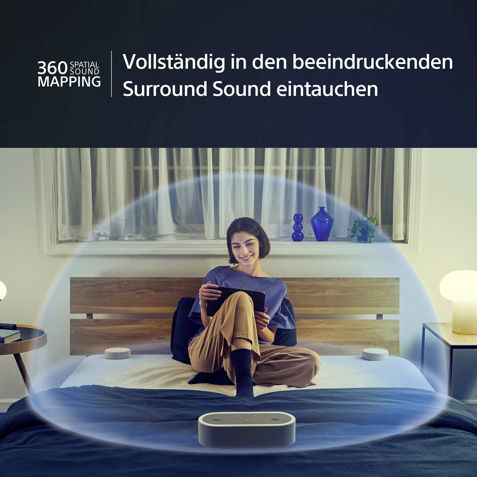 Una persona è seduta su un letto e sta utilizzando un tablet. Intorno a lei è visibile una visualizzazione di un suono spaziale a 360 gradi.