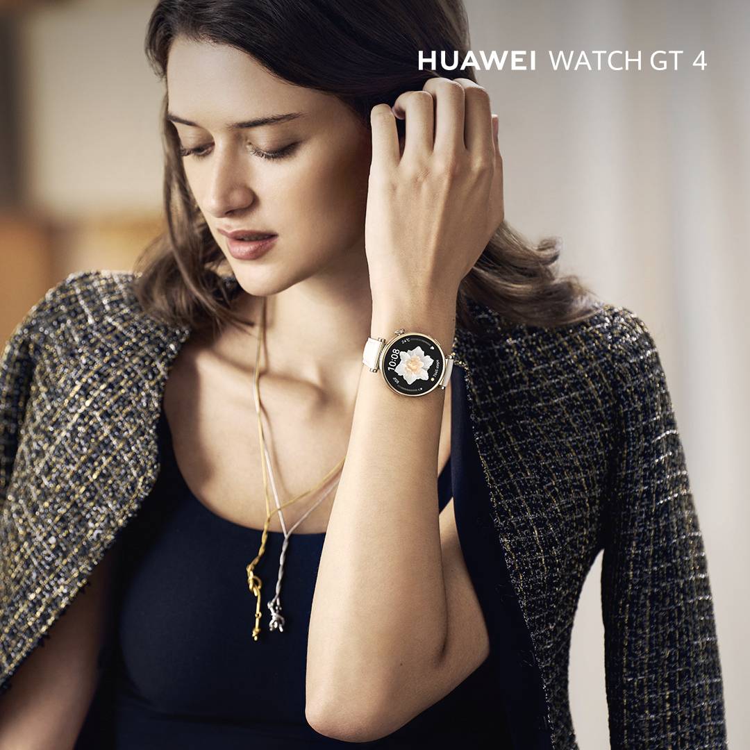 Una donna indossa la 'Huawei Watch GT 4', un cronografo elegante in stile lussuoso. È vestita in modo chic con un top simile a una giacca.