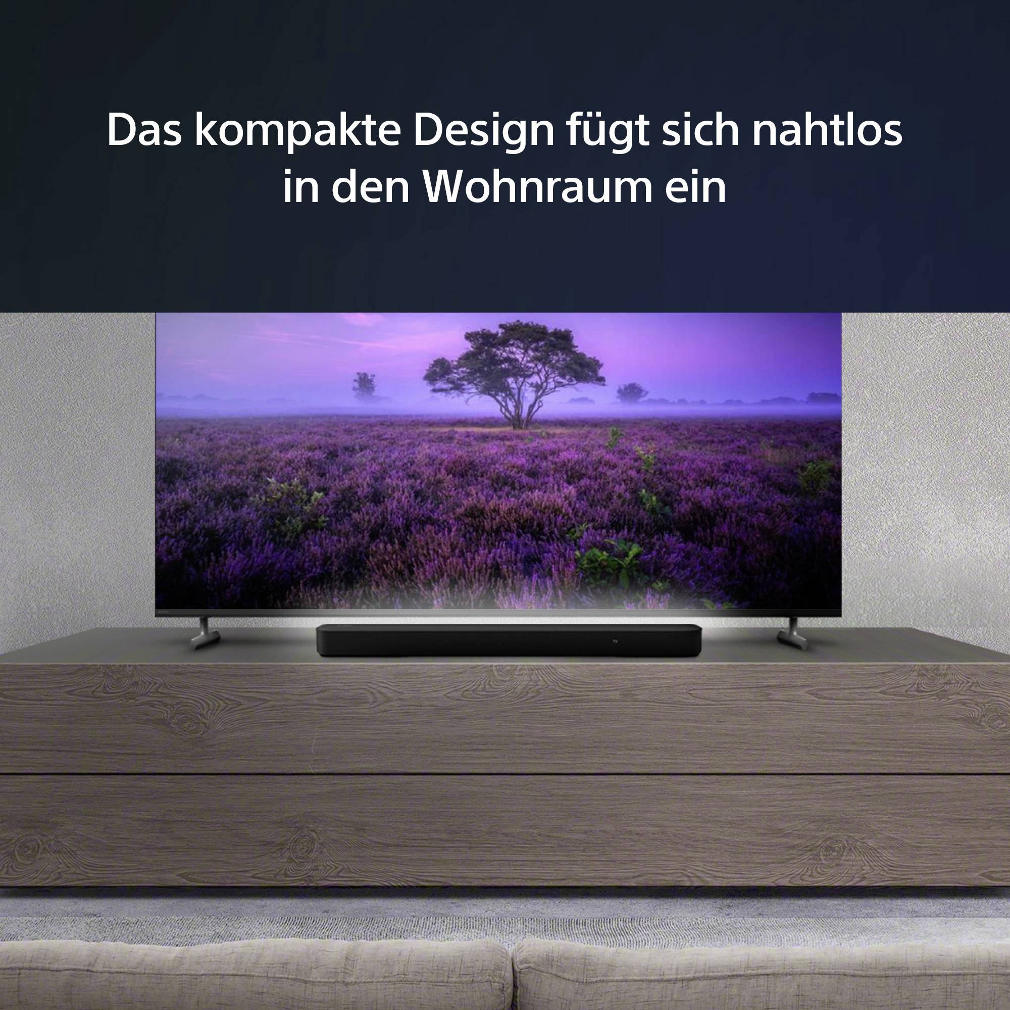 Un televisore moderno è poggiato su un mobile di legno. Lo schermo mostra un paesaggio lilla con un albero sotto un cielo viola.
