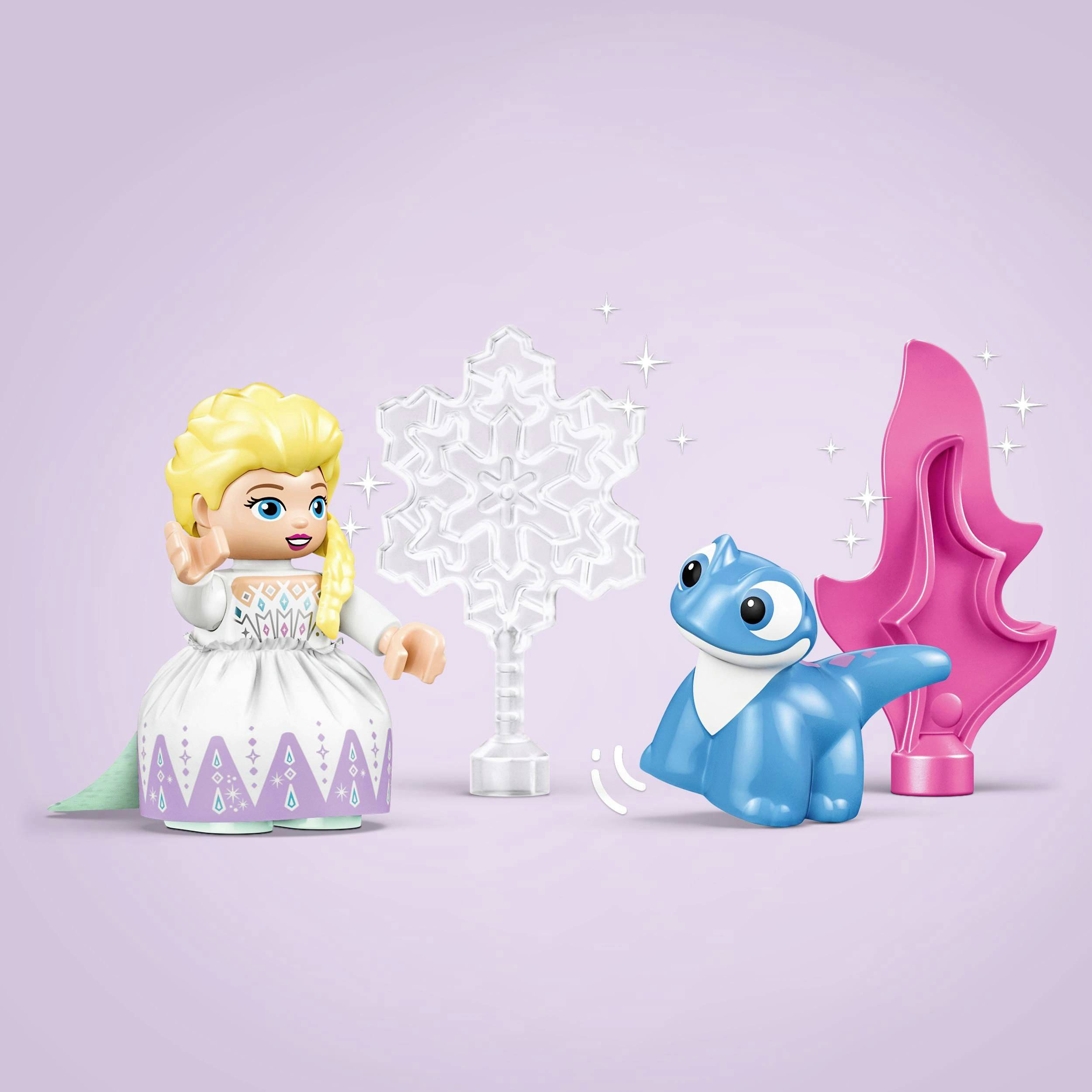 Piccola statuetta con capelli biondi e vestito viola è in piedi accanto a un drago giocattolo blu sullo sfondo a forma di fiocco di neve.