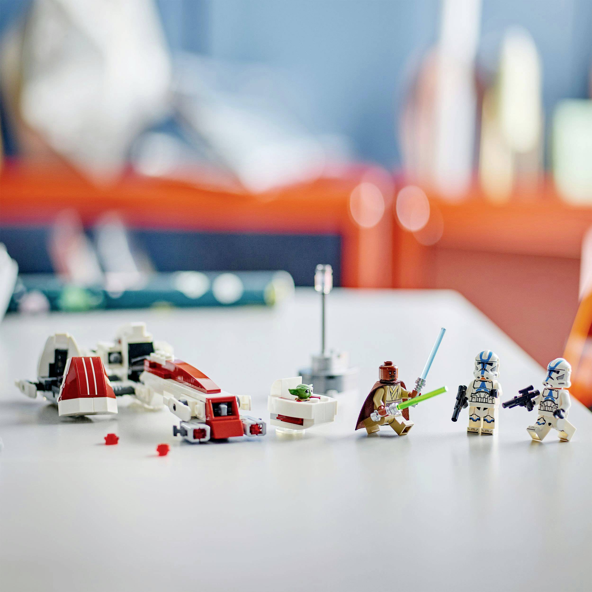 Sul tavolo sono sparse figure di Lego Star Wars e parti di astronavi. Tre figurine sono in piedi, circondante da mattoncini colorati.