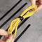 Una persona tiene un cavo Ethernet giallo legato con un fascetta nera. Sullo sfondo si vedono canali per cavi neri su un tavolo grigio.