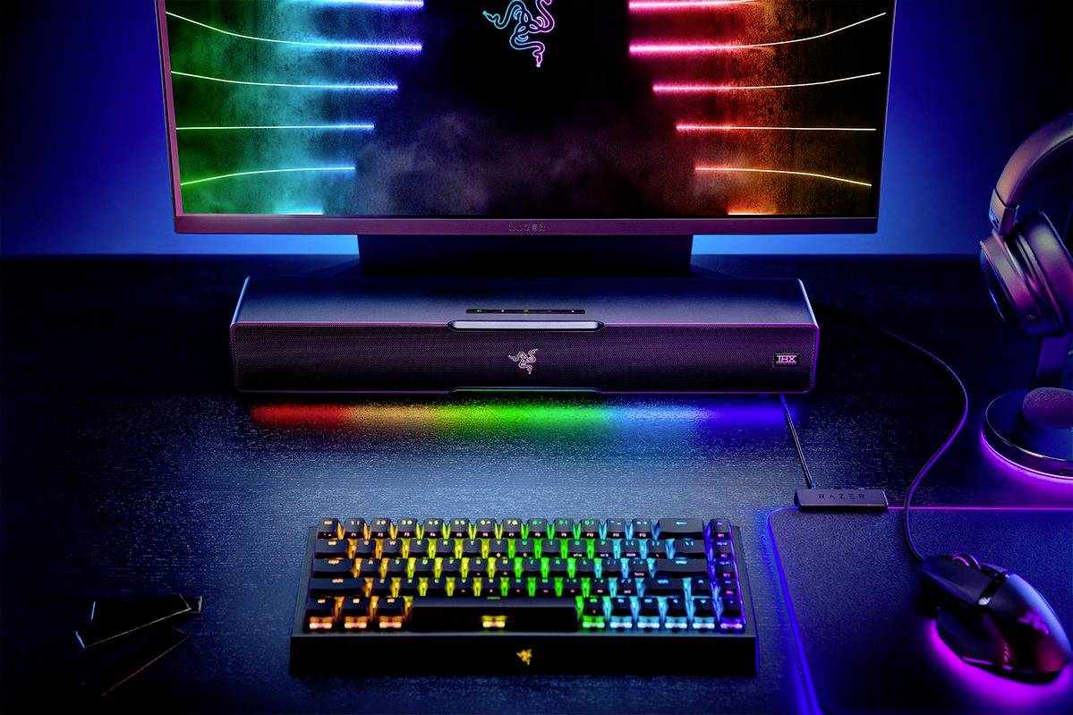 Scrivania per computer con tastiera retroilluminata RGB, tappetino per mouse, monitor con sfumatura di colore sullo schermo, soundbar e cuffie.