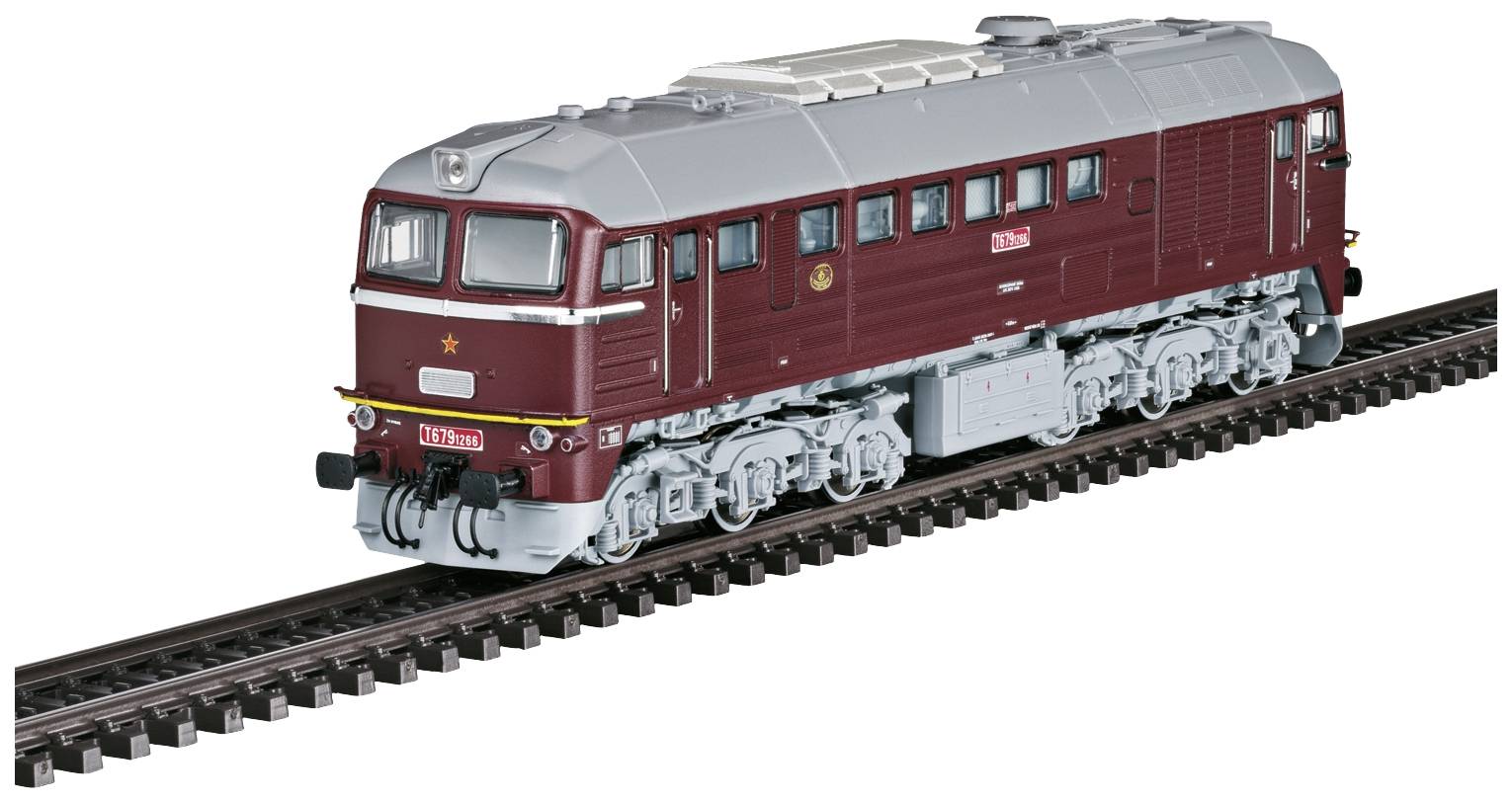 Un trenino rosso scuro con un tetto grigio sta viaggiando sui binari. Il treno ha una parte anteriore rettangolare e ruote argentate.