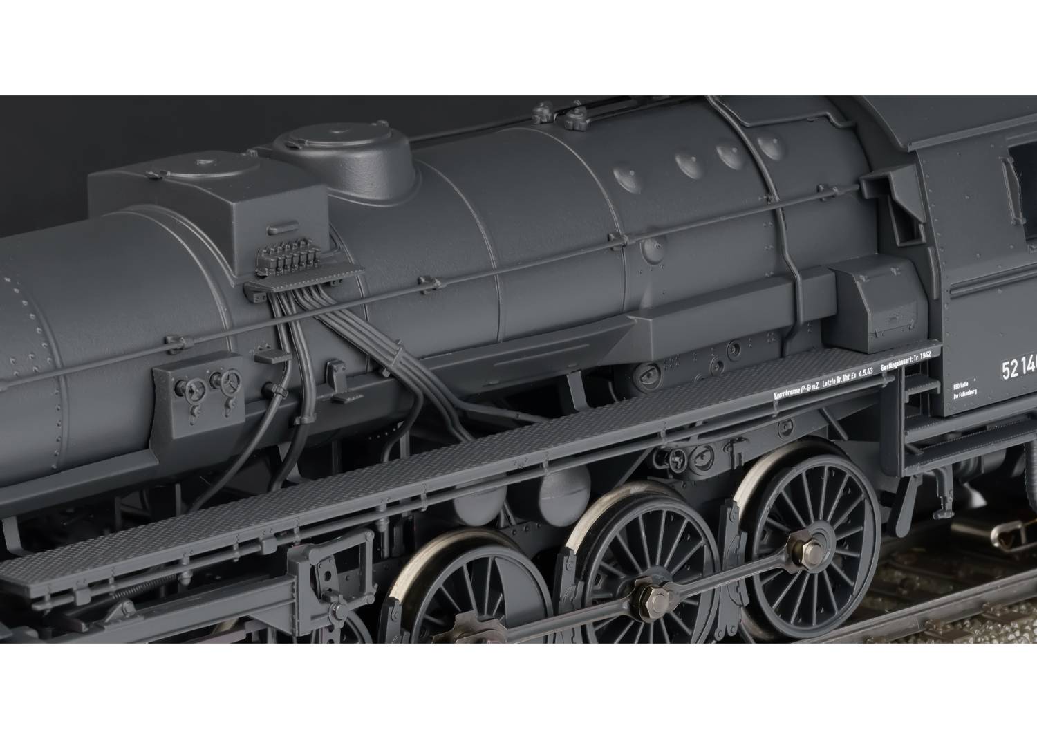 Locomotiva a vapore nera della serie 52 in formato modellino, ripresa lateralmente, con ruote e caldaia visibili.