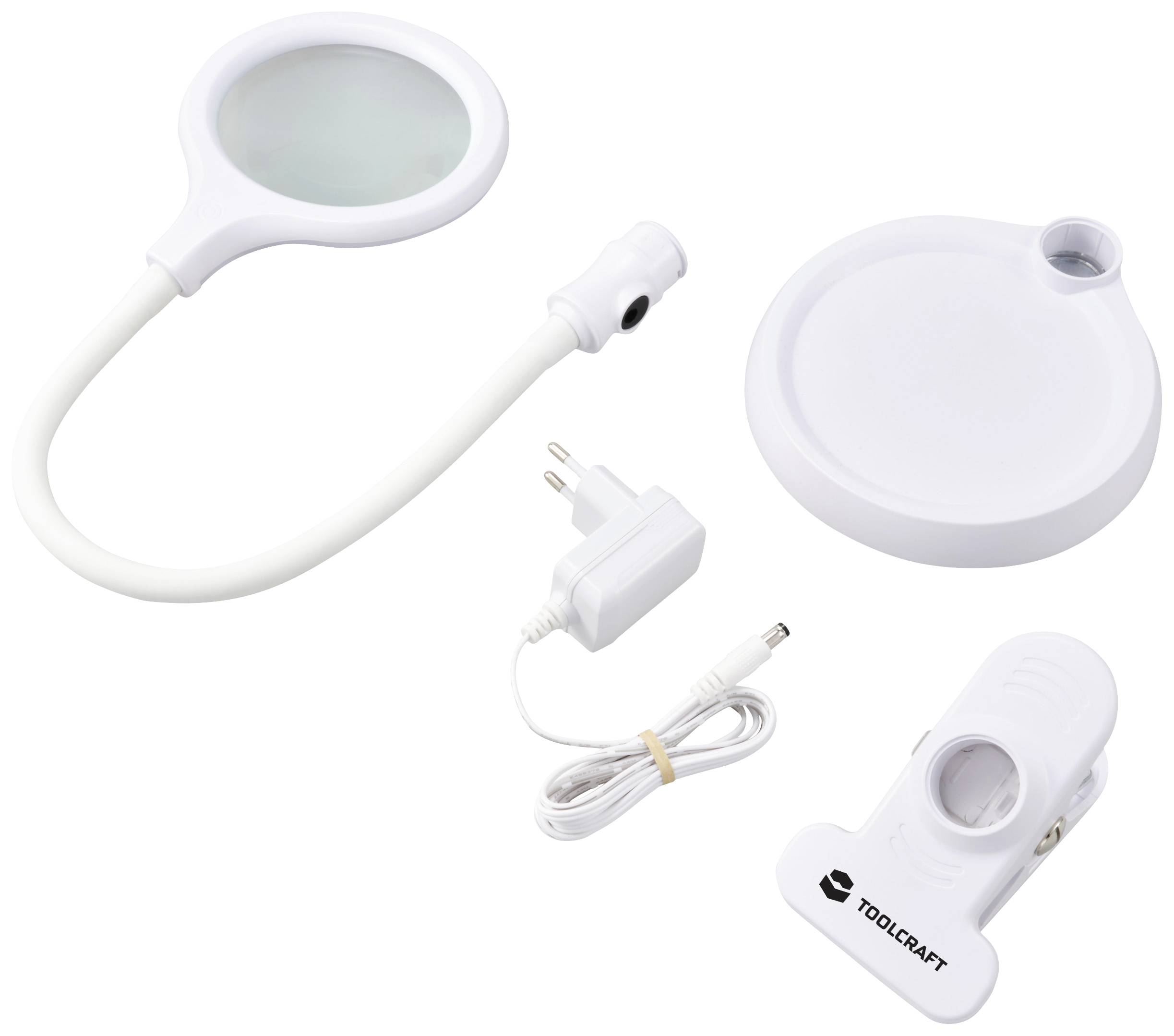 Una piccola lente d'ingrandimento LED rotonda con braccio flessibile, base, adattatore di rete e un clip di fissaggio con il logo 'Toolcraft'.