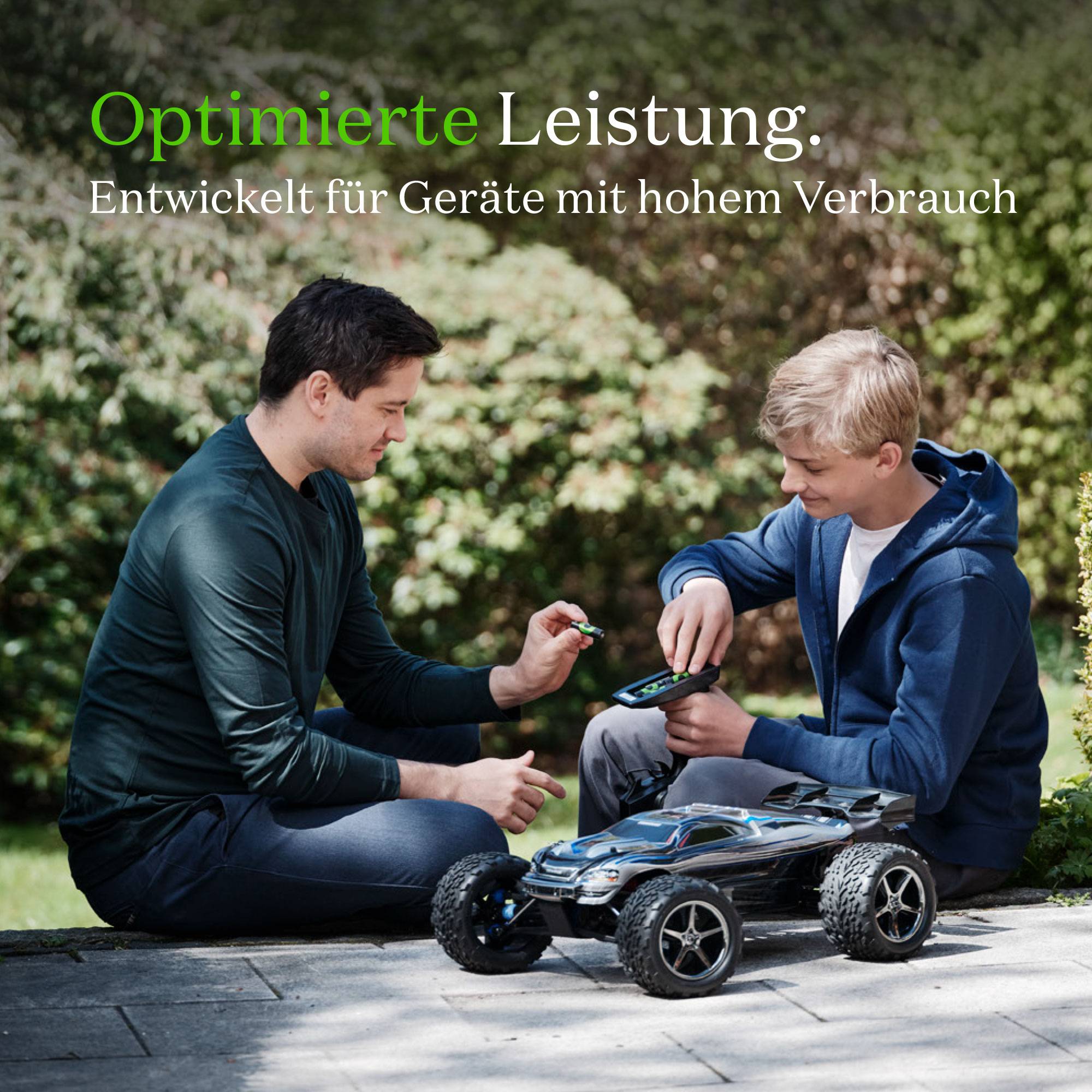 Due persone siedono all'esterno, concentrate su un'auto radiocomandata. Testo in alto: 'Prestazioni ottimizzate. Sviluppato per dispositivi ad alto consumo.'