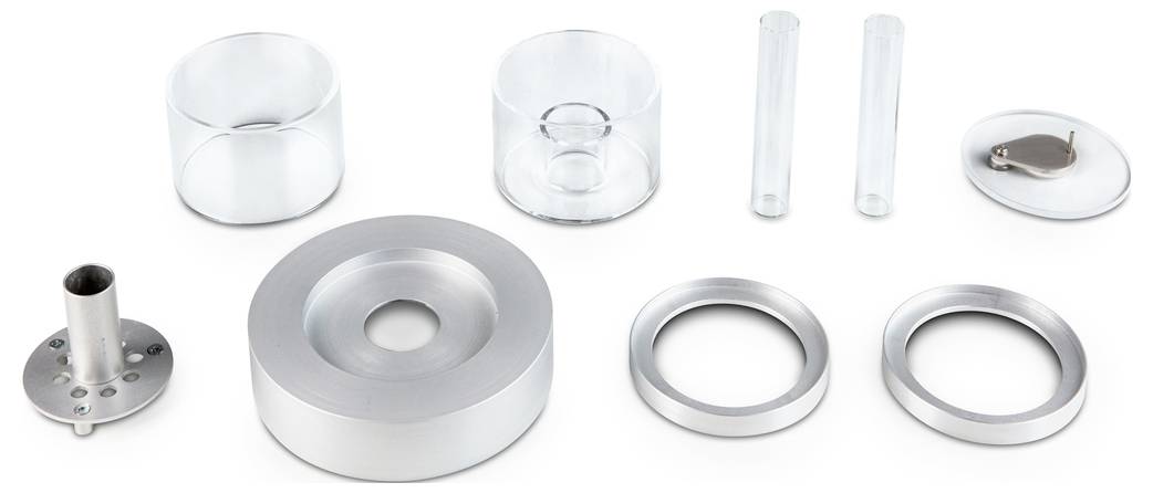 Un set di componenti in vetro e metallo di varie forme e dimensioni, compresi anelli, cilindri e tubi, su sfondo bianco.