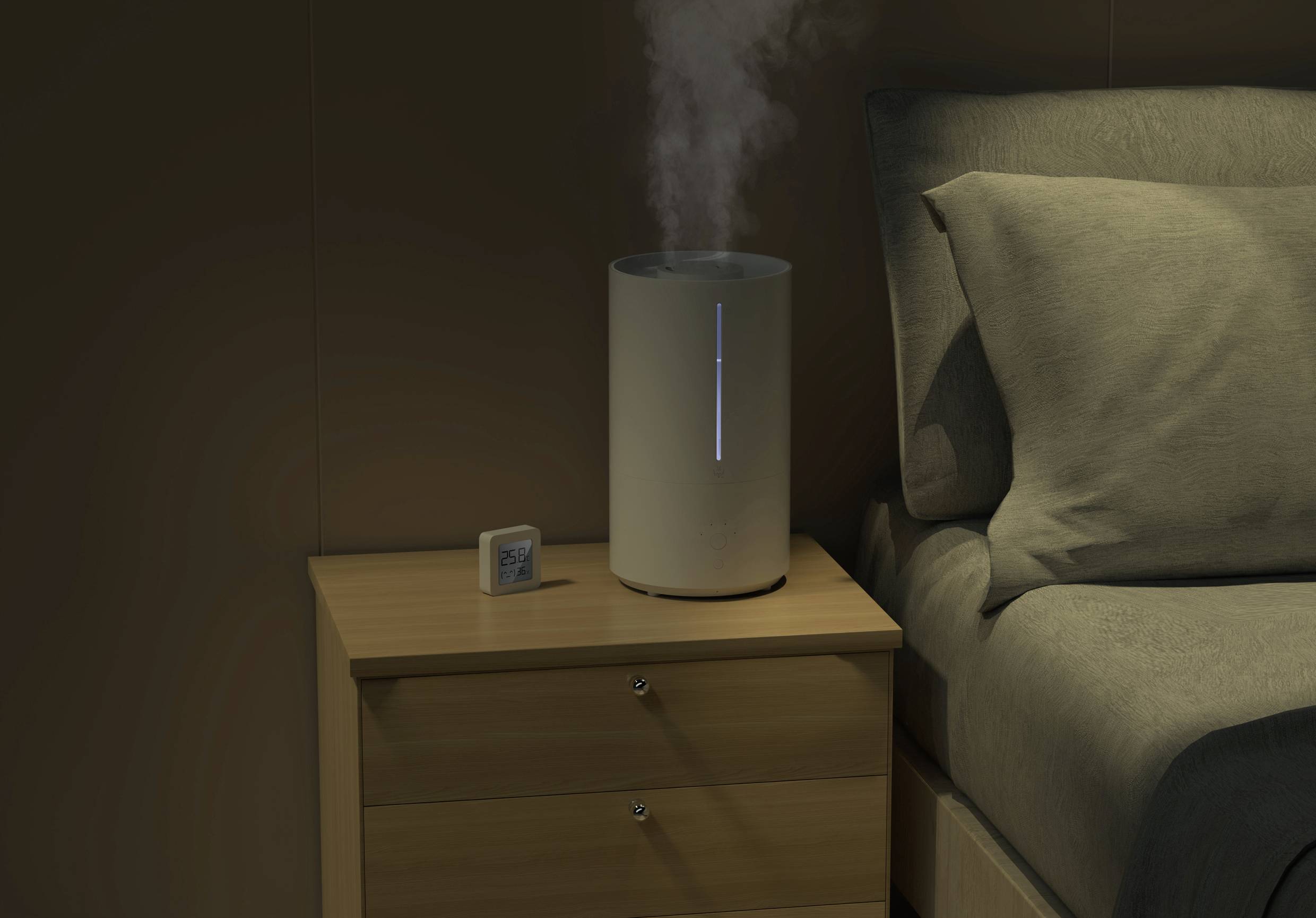 Umidificatore su un comodino accanto a un letto, che emette vapore. Accanto è posizionato un piccolo termometro-igrometro digitale.