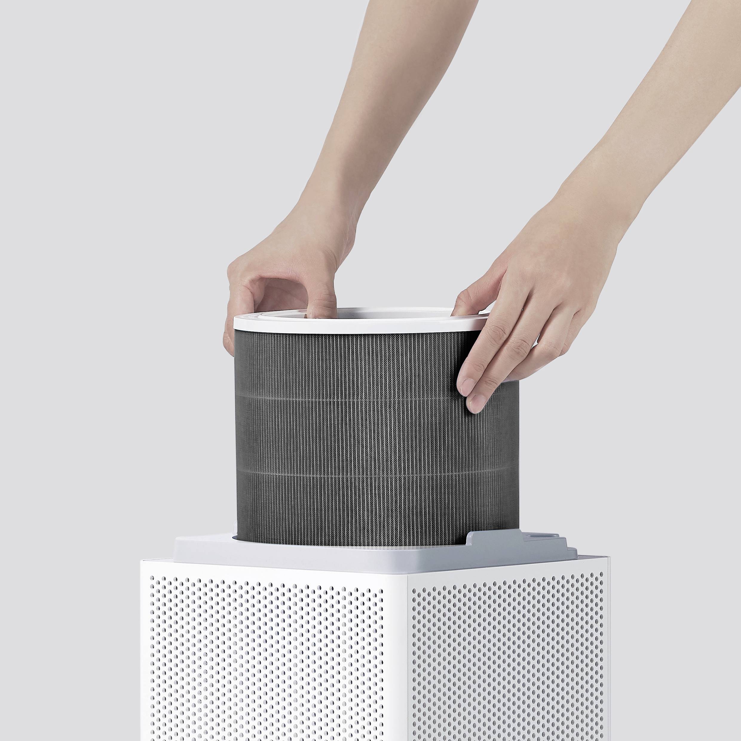 Una persona sta montando un filtro rotondo su un purificatore d'aria con una cassa bianca e una superficie perforata.