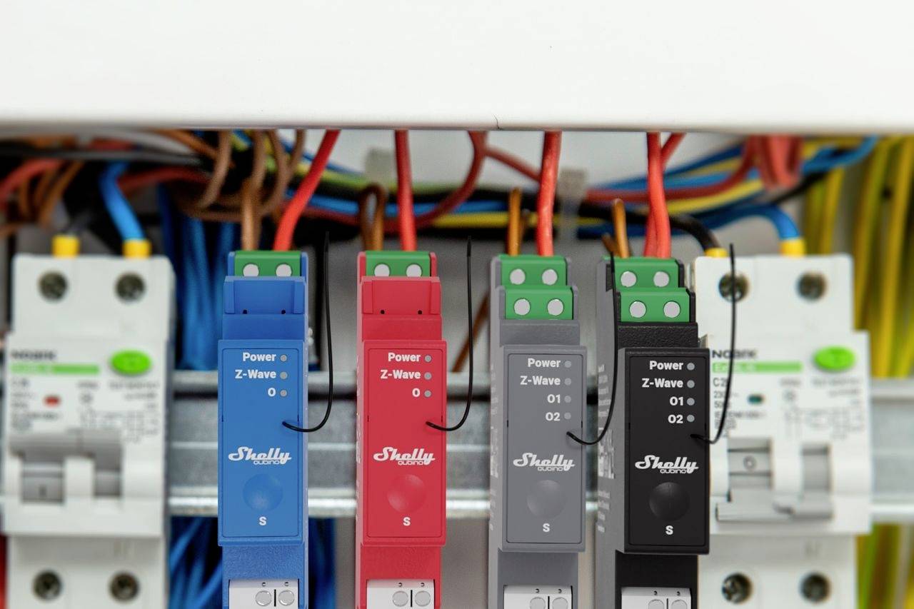 Scatola di sicurezza con quattro sensori di corrente Shelly collegati in serie, ciascuno collegato con cavi colorati, mostra la gestione dell'energia elettrica.