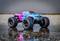 Monster truck giocattolo blu e rosa riflesso sull'asfalto bagnato. Pneumatici massicci, carrozzeria moderna, design dinamico.