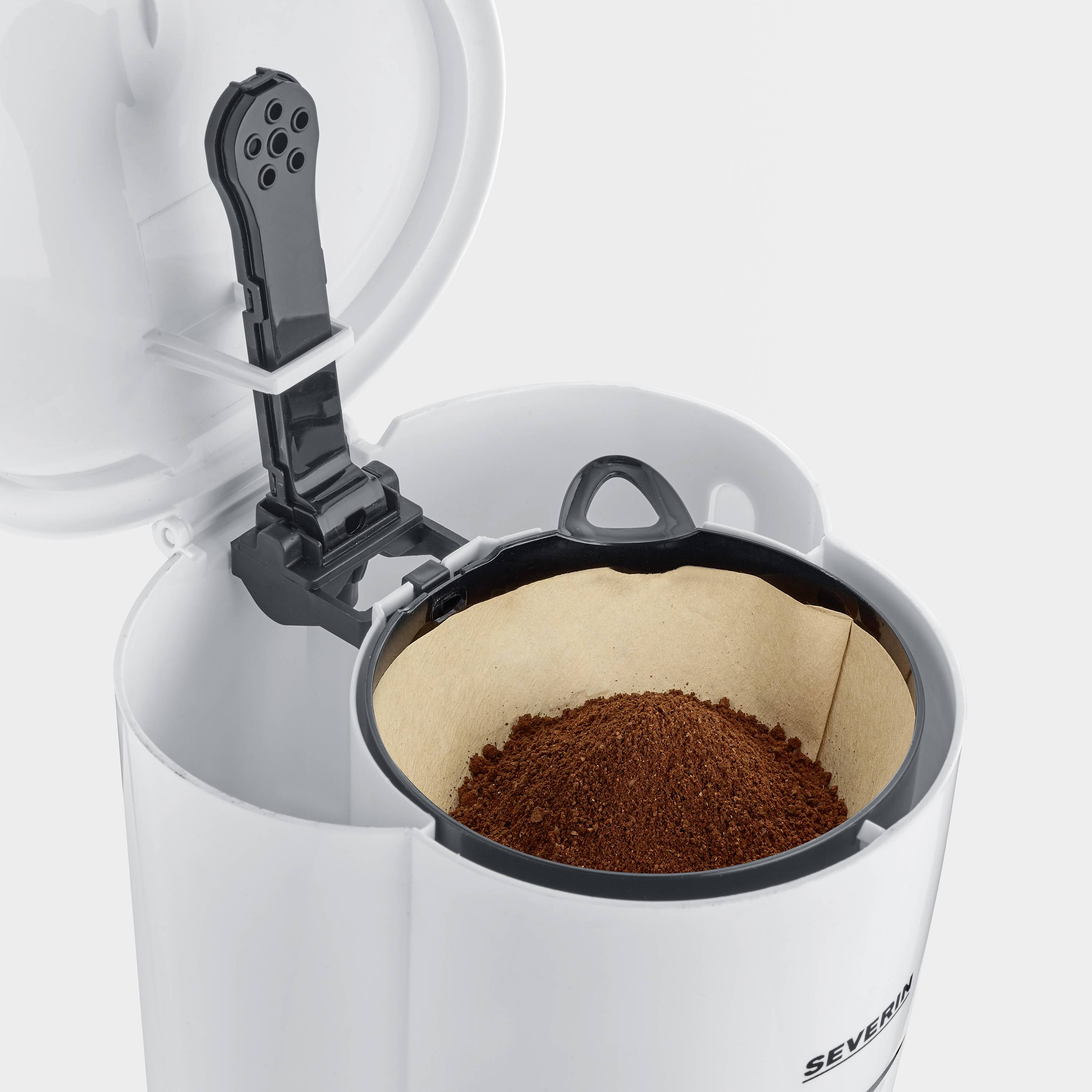 Una macchina da caffè con il coperchio aperto mostra un filtro con caffè appena macinato.