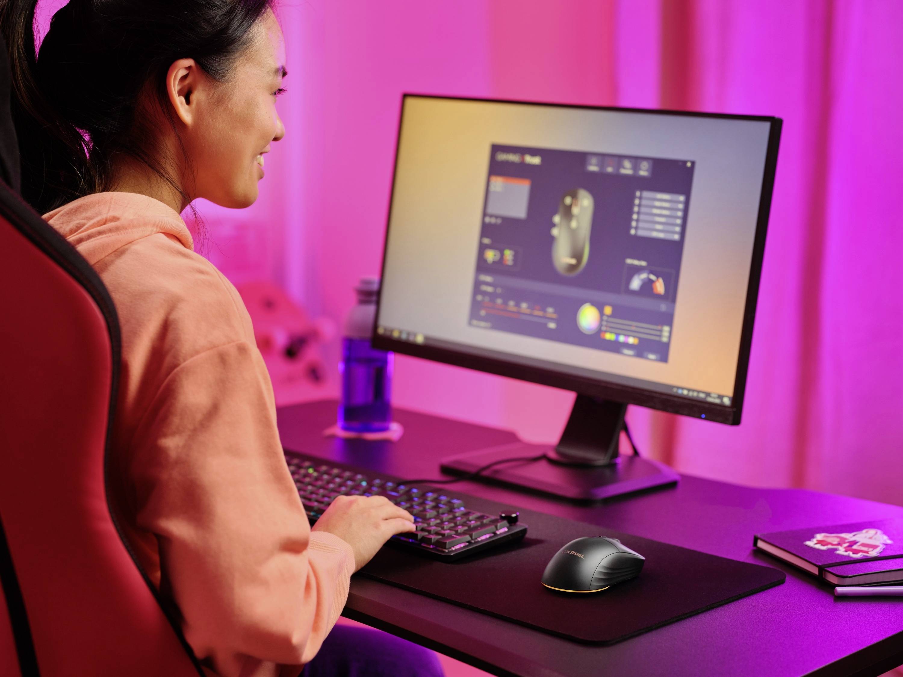 Una donna lavora a una scrivania con un computer, sul quale è aperto un programma per la configurazione delle impostazioni del mouse.