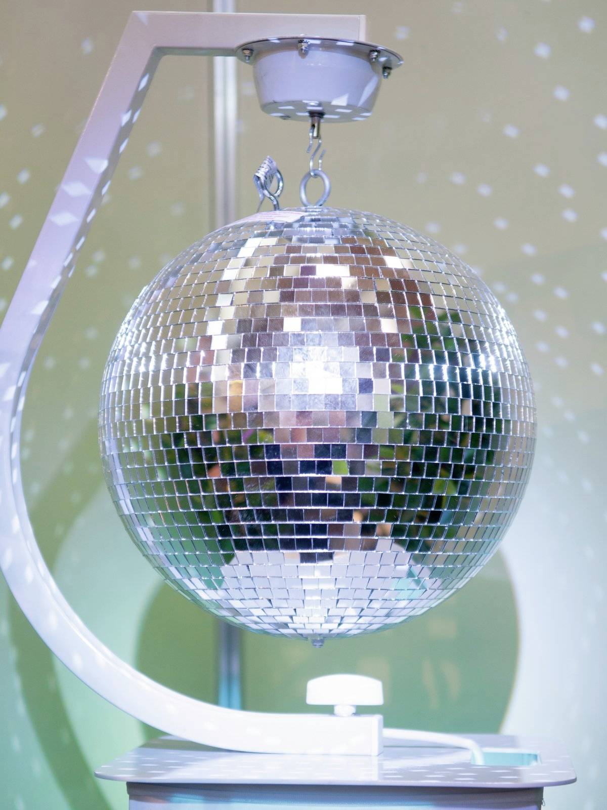 Una palla a specchio da discoteca è appesa a un supporto, riflette punti di luce e crea un'atmosfera vivace nella stanza.
