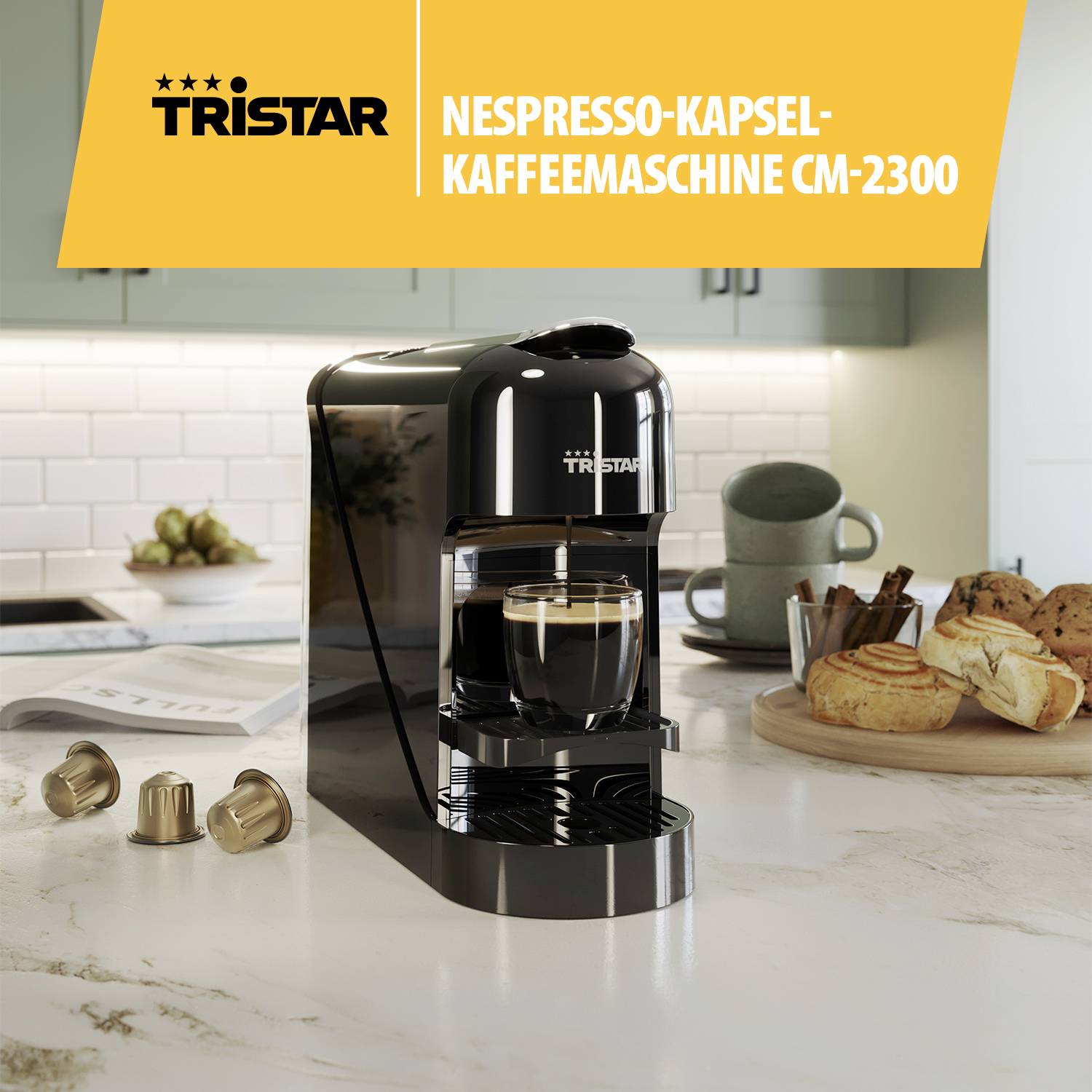 Una macchina da caffè Nespresso nera di Tristar è posizionata sul piano di lavoro di una cucina moderna, circondata da tazze da caffè e dolci.