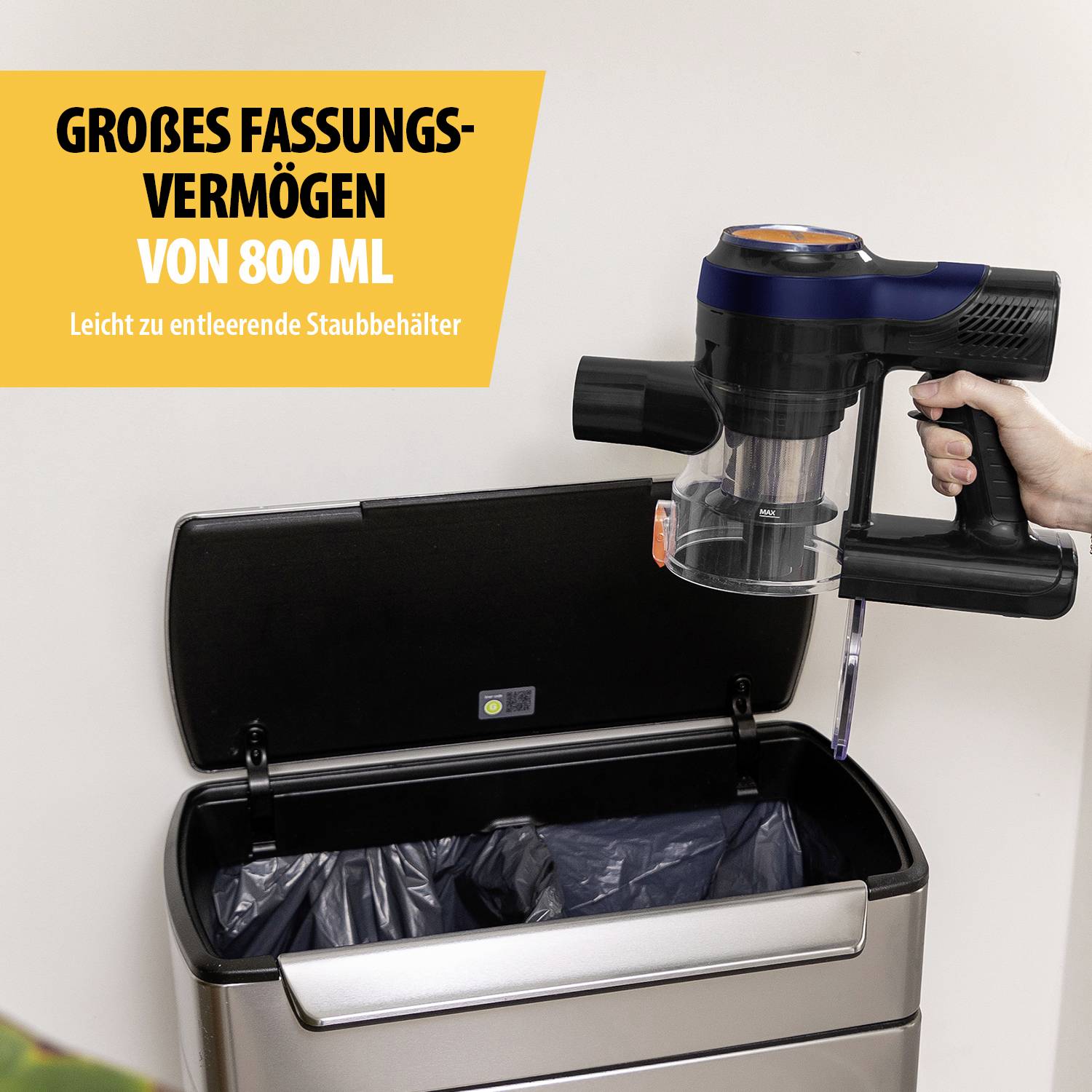 "Grande capacità di 800 ml" è scritto su un cartello. Una mano sta azionando un aspirapolvere mentre svuota il suo contenitore in un cestino dei rifiuti.