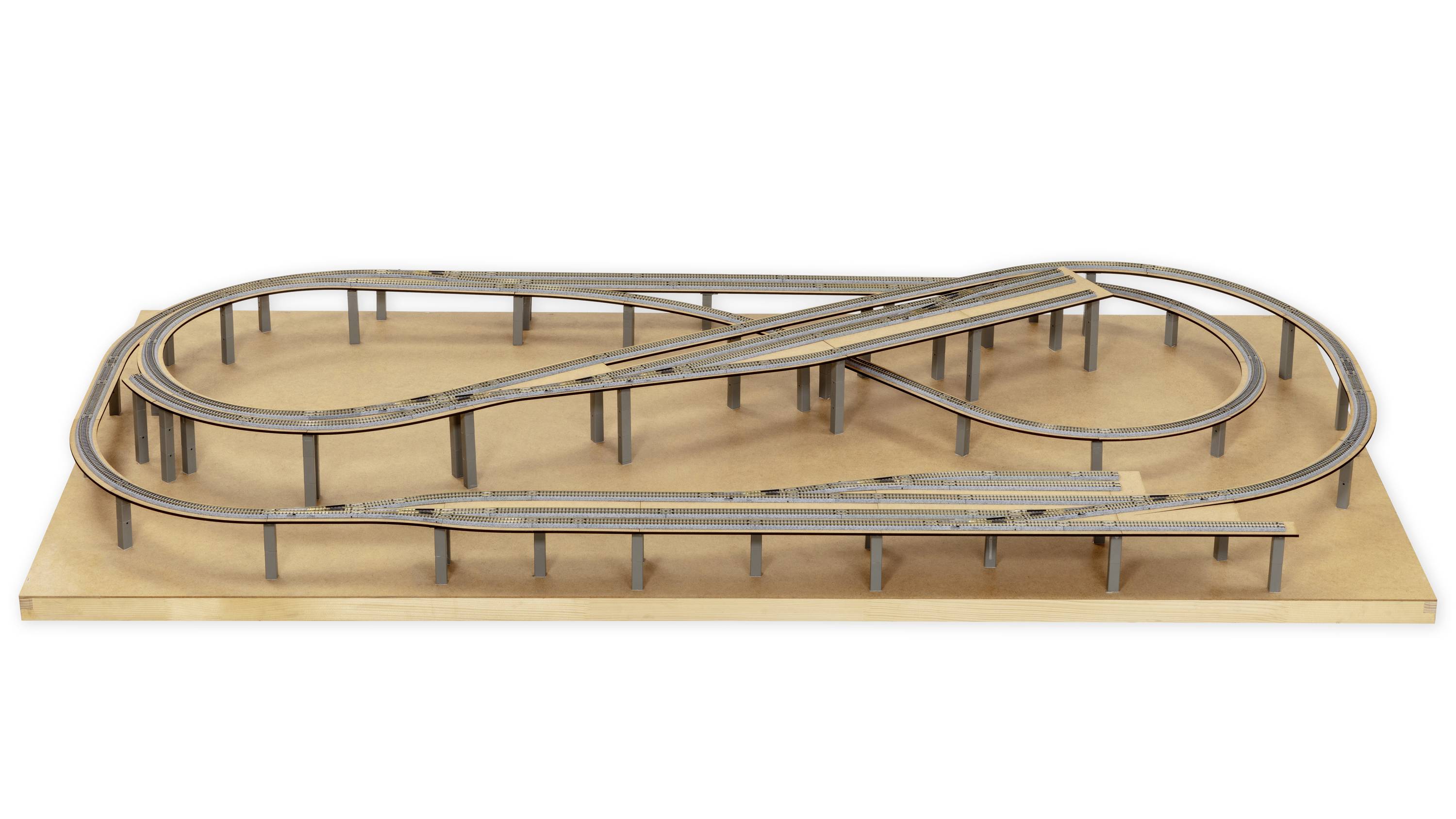 Ponte ferroviario in miniatura su tavola di legno, mostra un percorso complesso con più livelli e curve, simboleggia la pianificazione infrastrutturale.