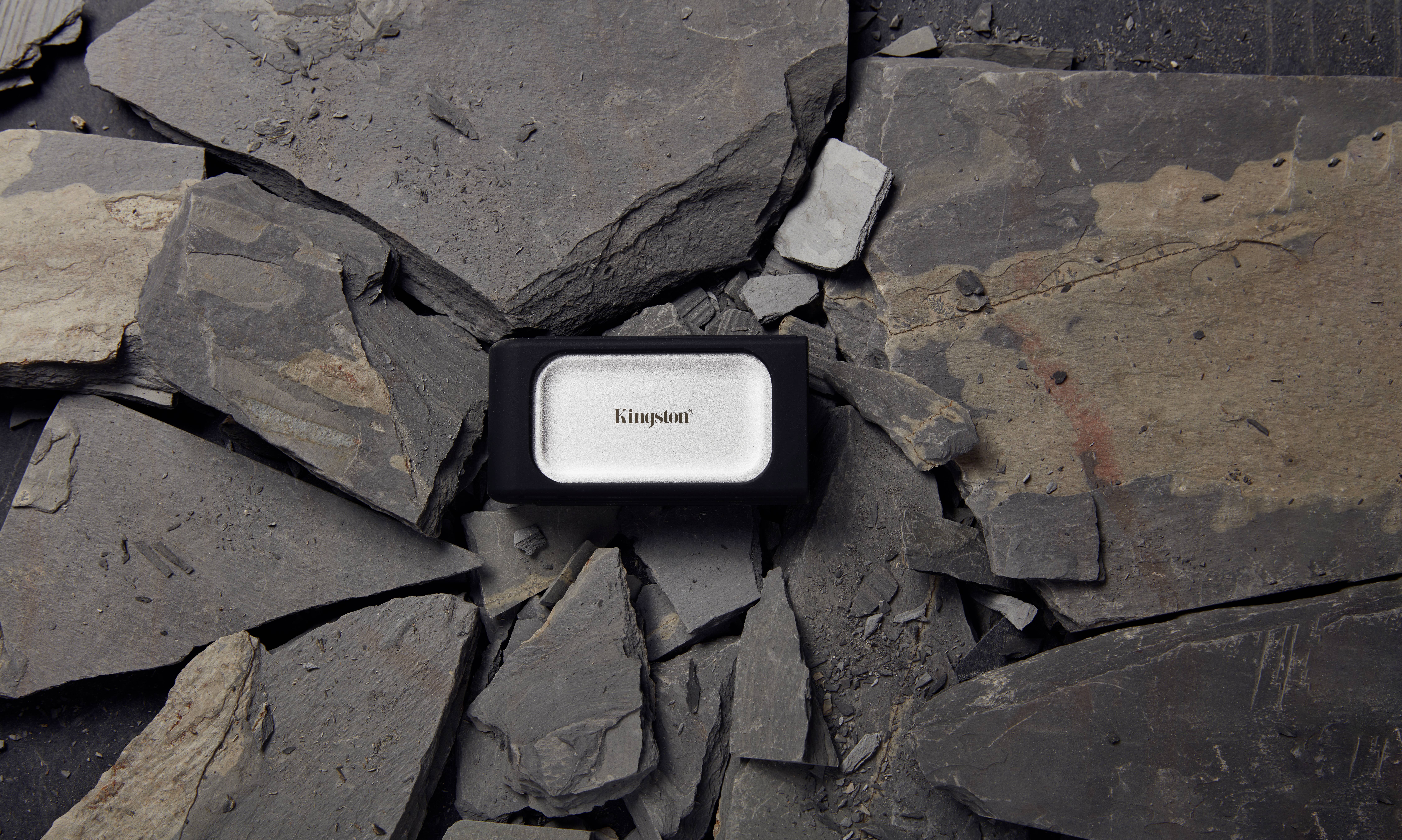 Un hard disk esterno nero giace su lastre di ardesia frantumate, con la scritta 'Kingston' sull'unità.