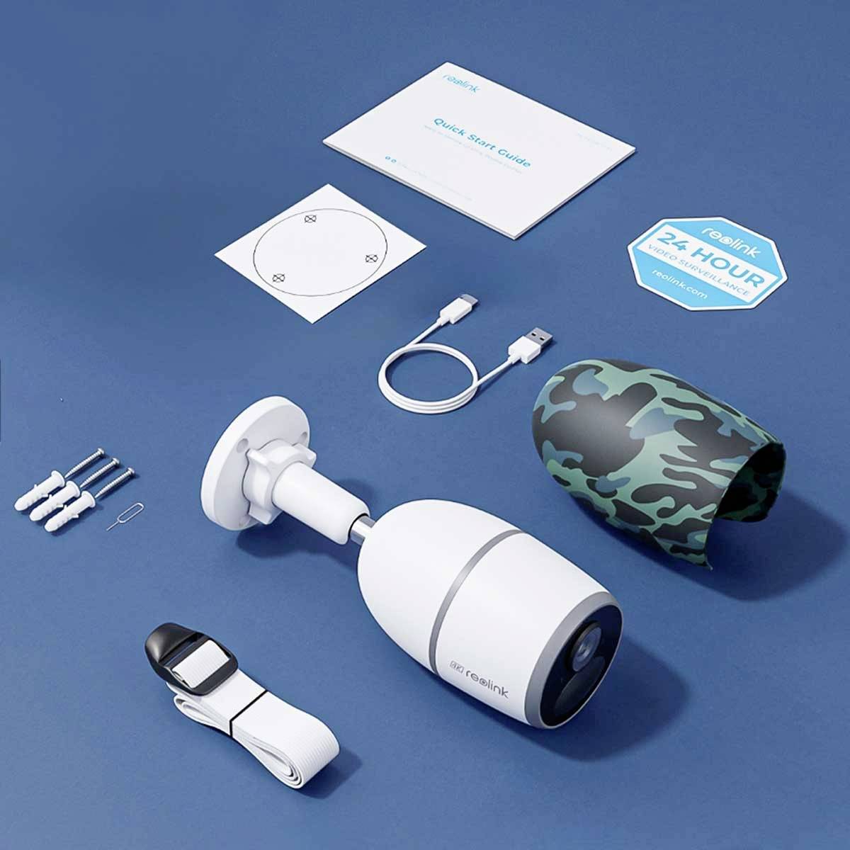 Telecamera di sorveglianza con accessori: telecamera, supporto, cavi, viti, istruzioni e custodia mimetica presentati su sfondo blu.